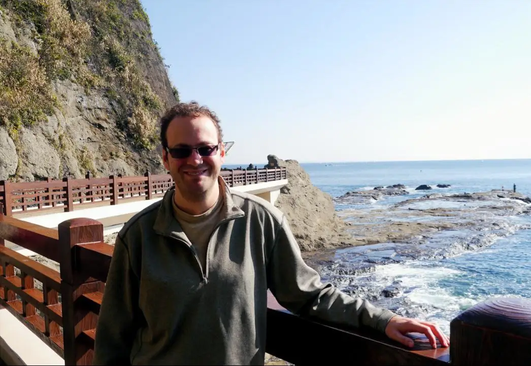 Author Matthew Lubin leaning on railing in front of ocean view