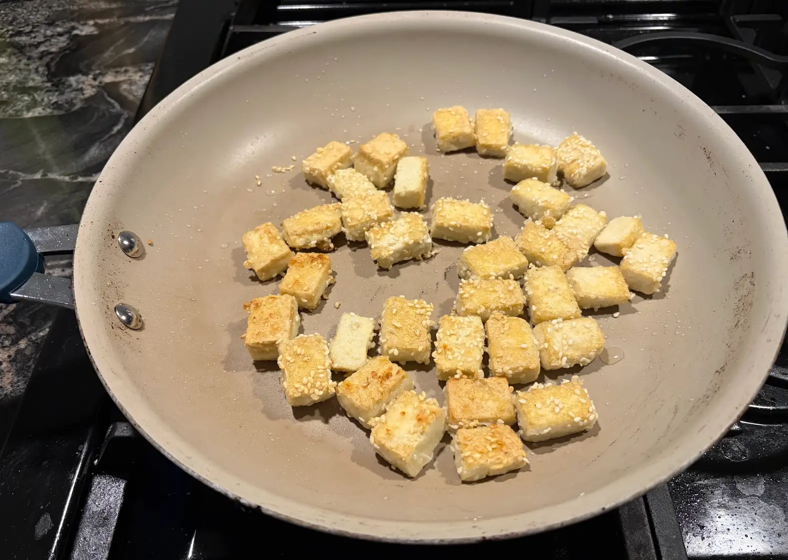 The writer frying the crispy tofu on a stovetop.