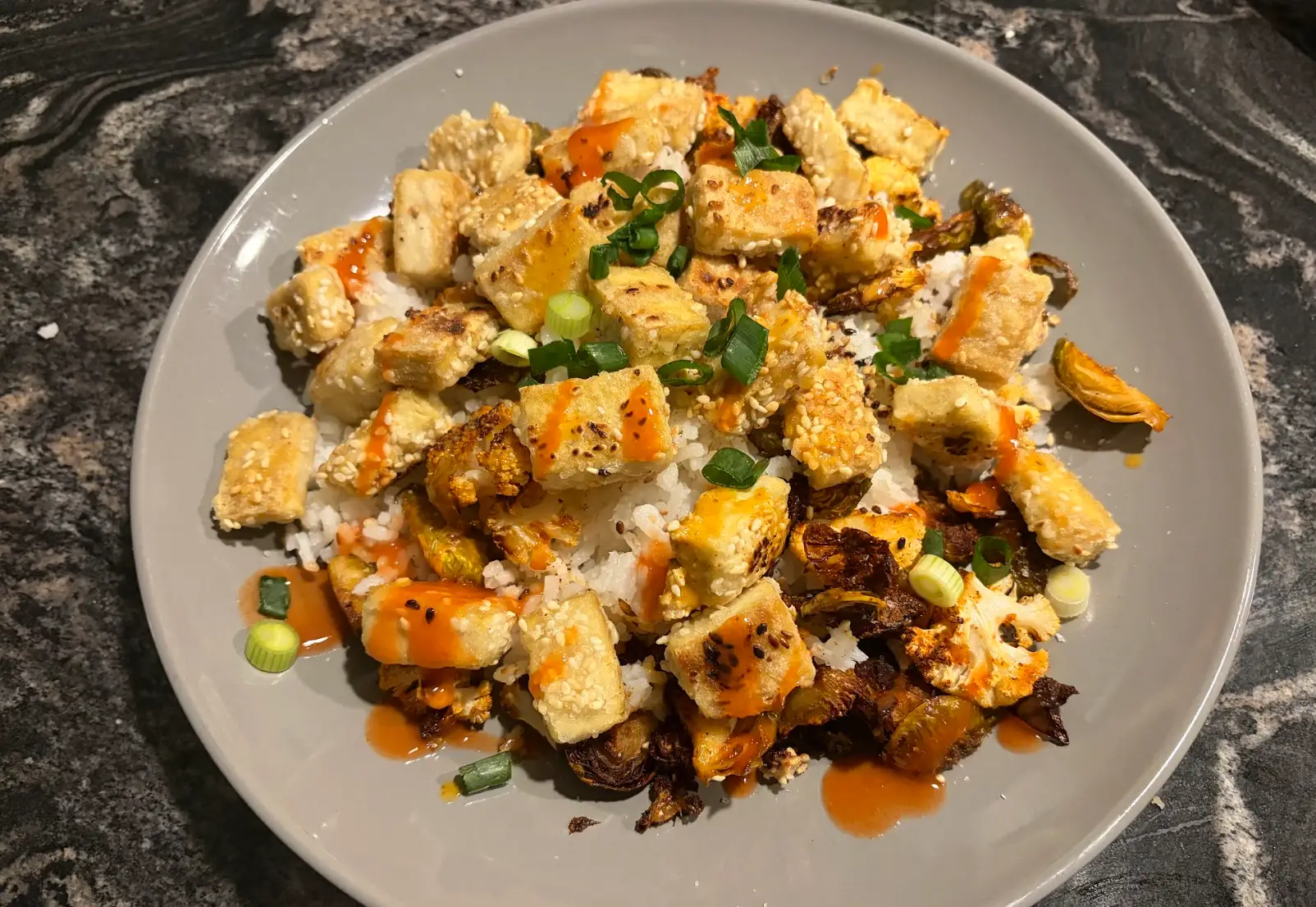 The tofu in a bowl with scallions, Brussels sprouts, cauliflower, and rice.