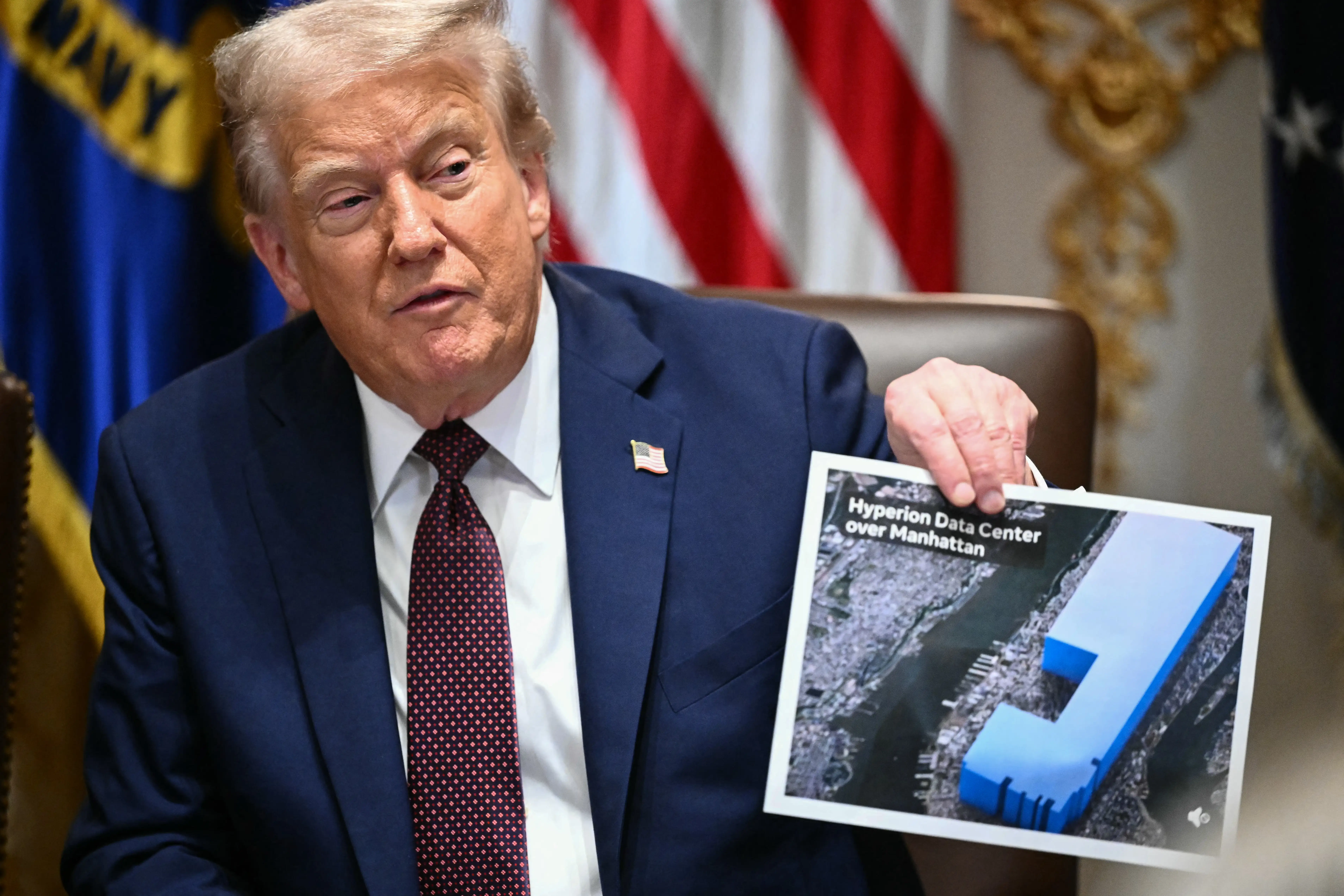 US President Donald Trump holds an image showing the size of Meta's new data center, during a cabinet meeting in the Cabinet Room of the White House in Washington, DC.