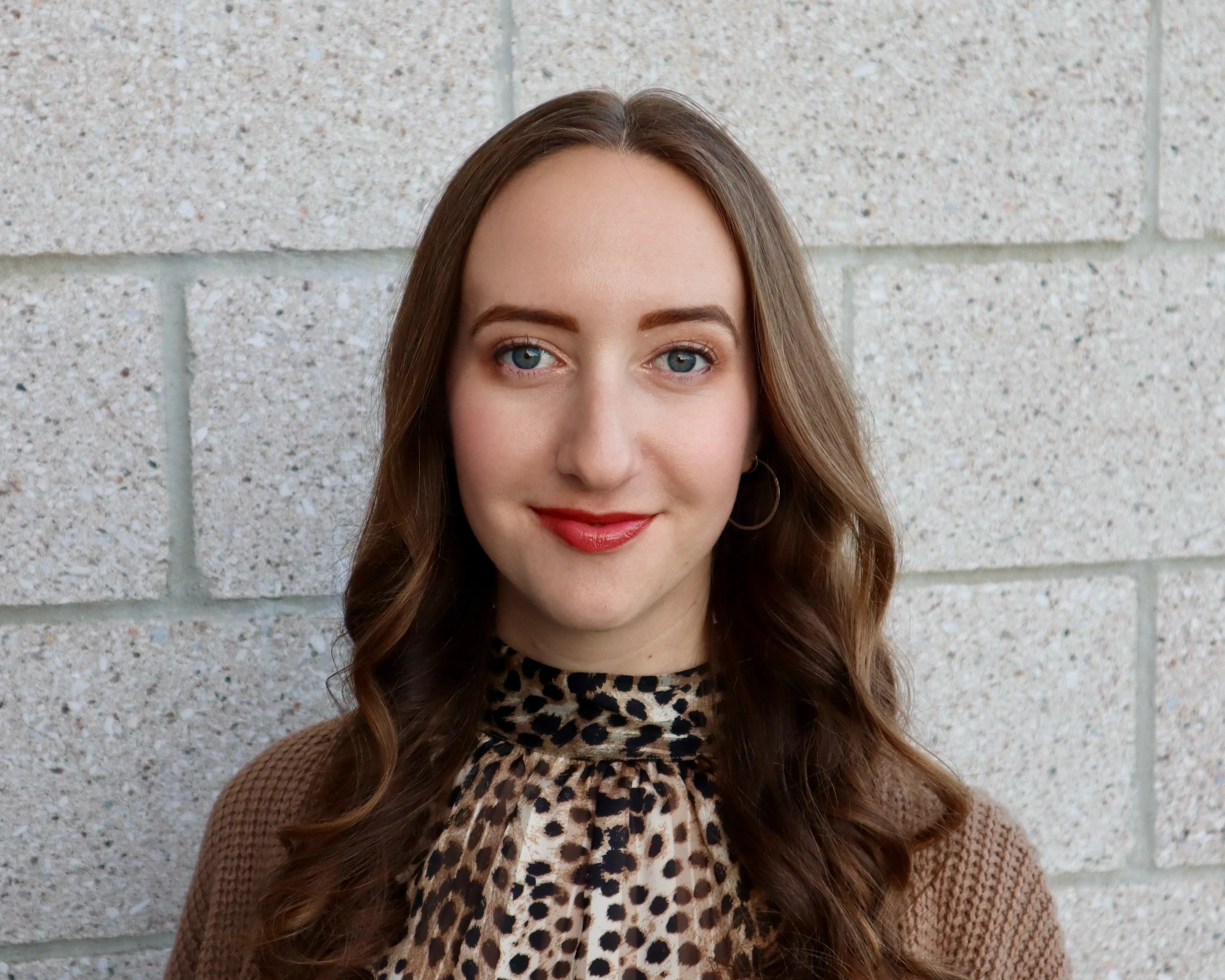 headshot of a woman in front of a light brick wall