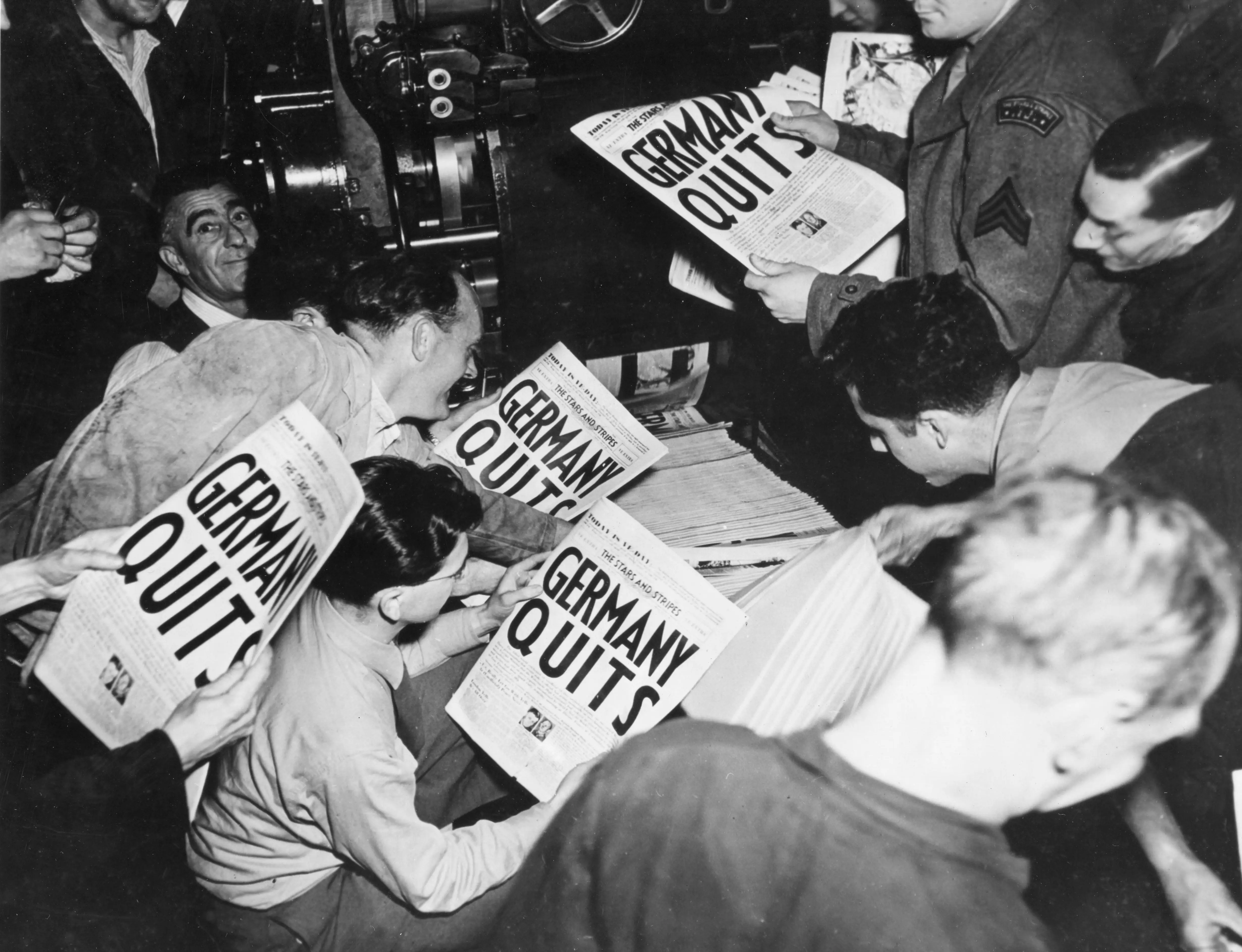 Allied soldiers read copies of the Stars and Stripes military newspaper announcing Germany's surrender in World War II, London, England, May 7, 1945