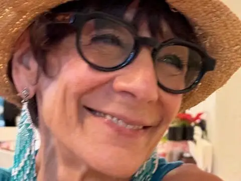 A woman wearing glasses, a hat, and dangly earrings.