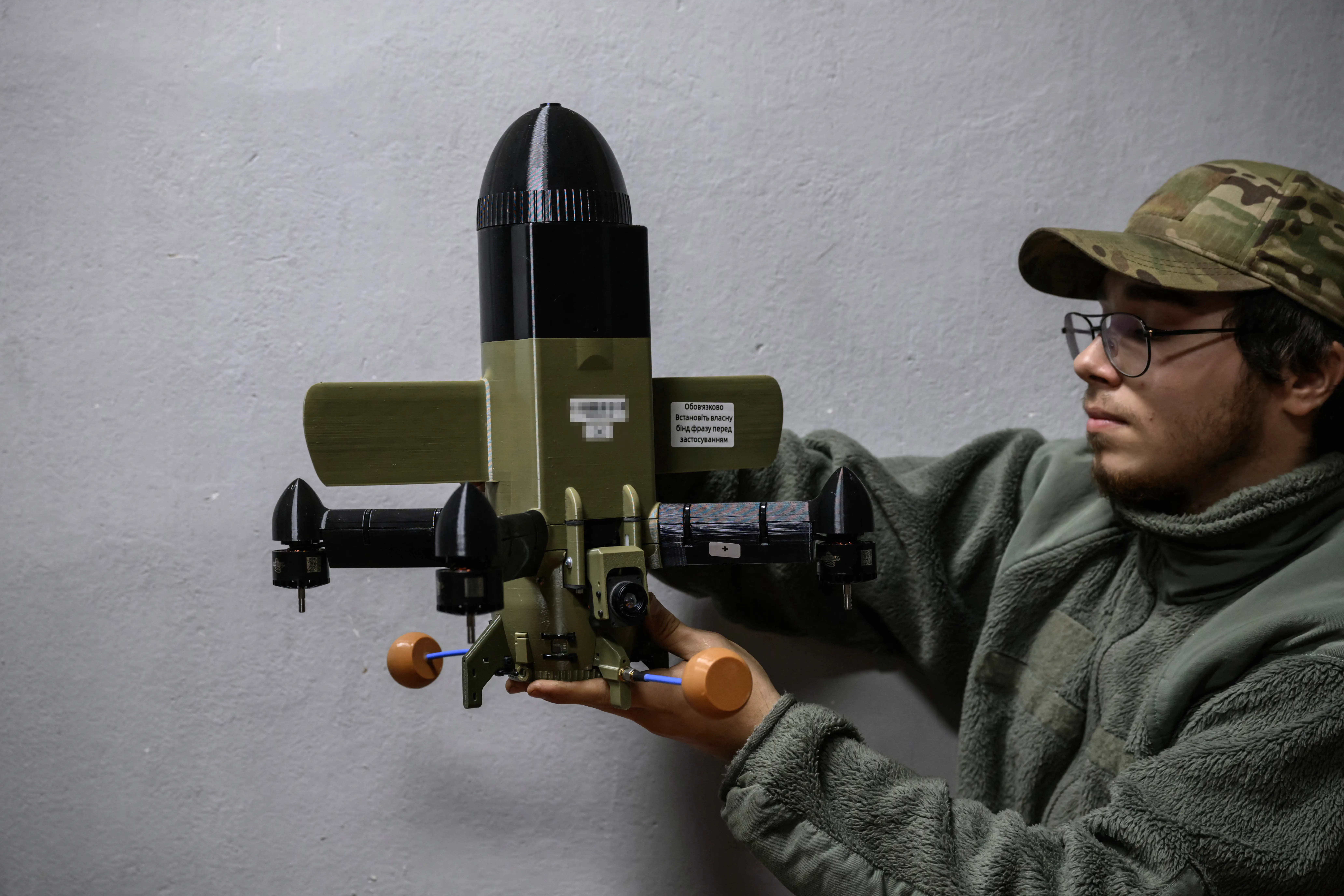 A Ukrainian man holds up a two-foot interceptor, which features a dome-shaped head and four propellers.