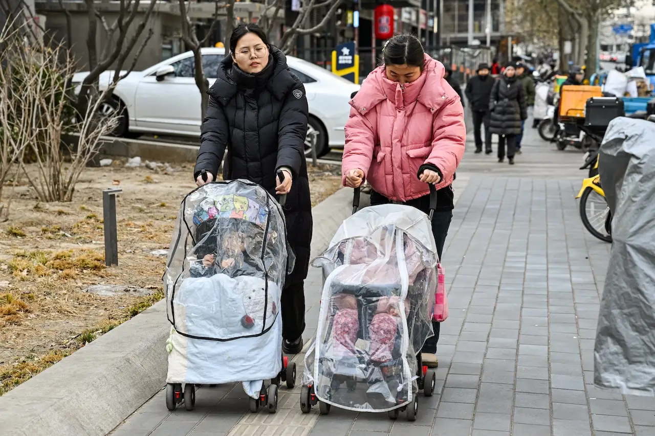 Women push baby strollers as they walk along a street in Beijing.