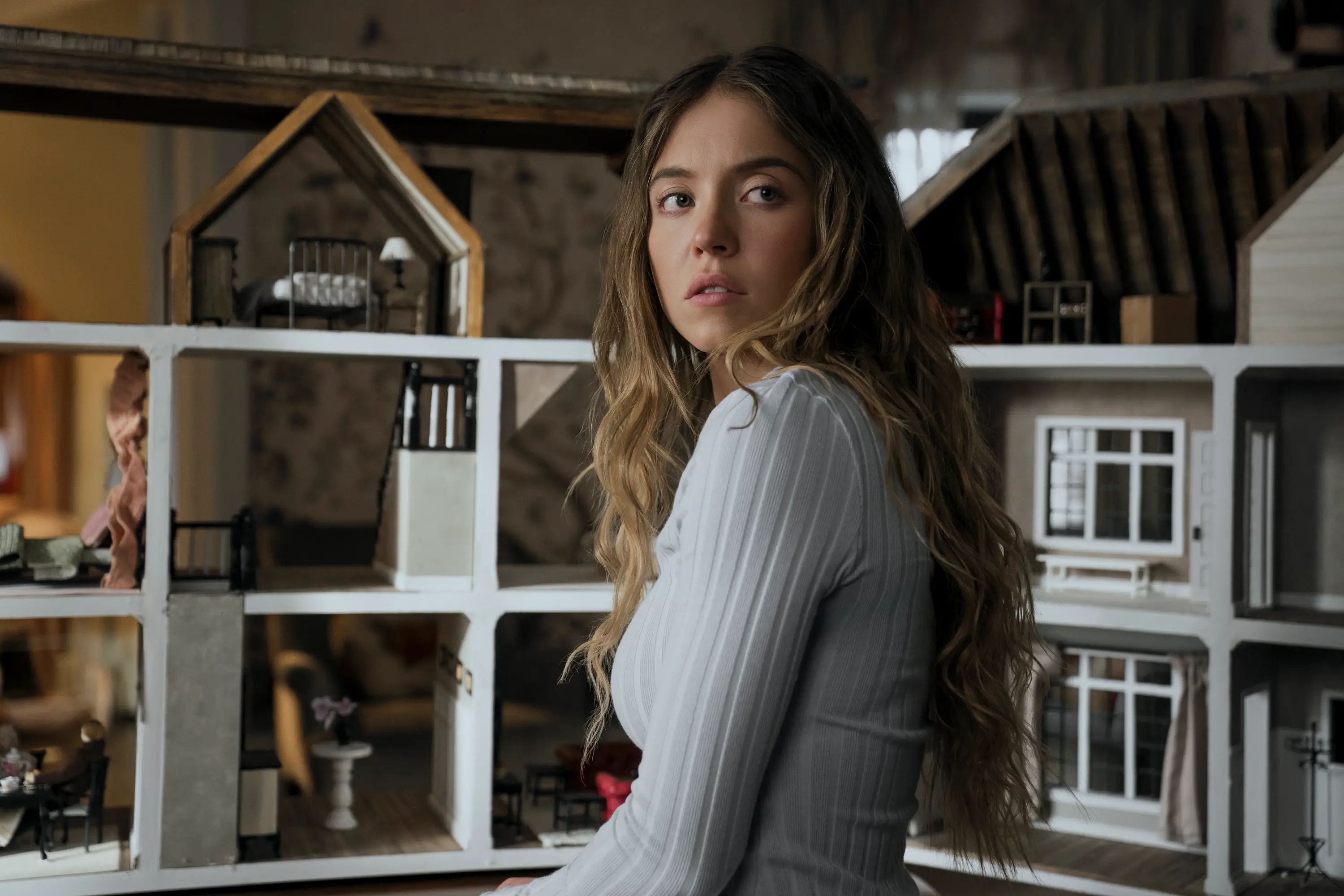 Sydney Sweeney sitting next to a doll house in The Housemaid