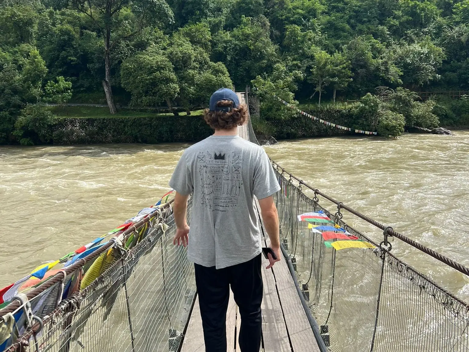 The author walking across a bridge in Bhutan; his back is to the camera.