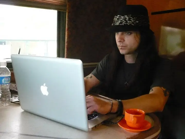 A man working on a laptop from a band's tour bus.