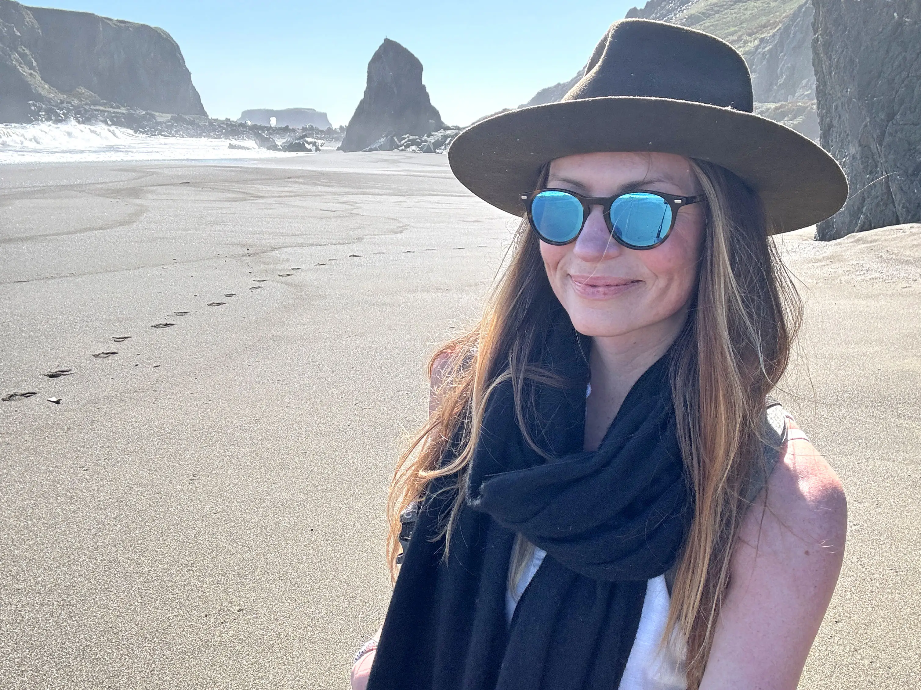 Emily wears sunglasses, a hat, and a scarf in a national park.