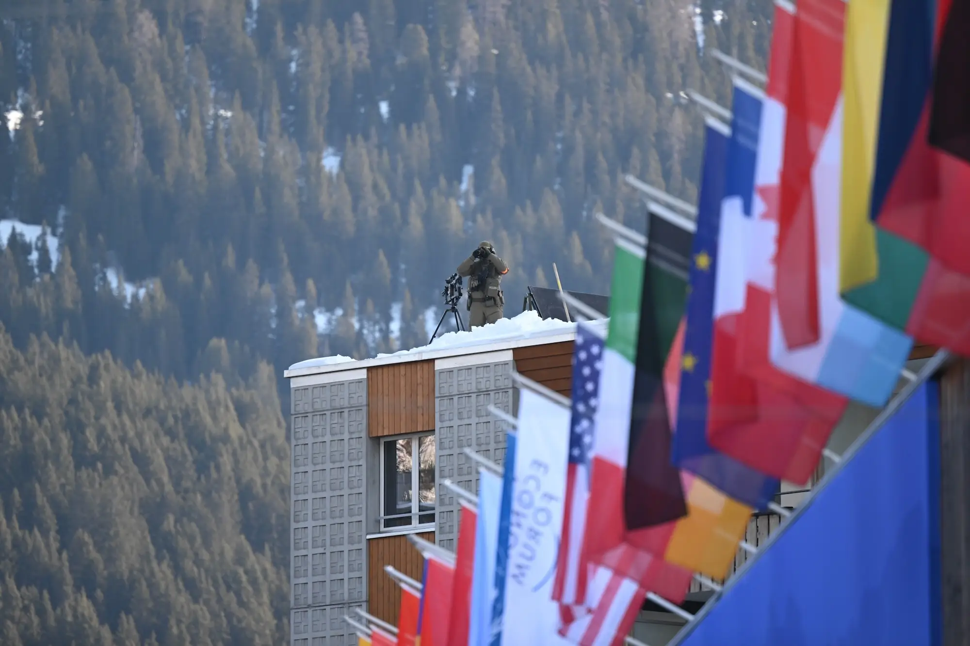 A sniper perched on a roof looks through binoculars at the World Economic Forum's annual meeting in Davos.