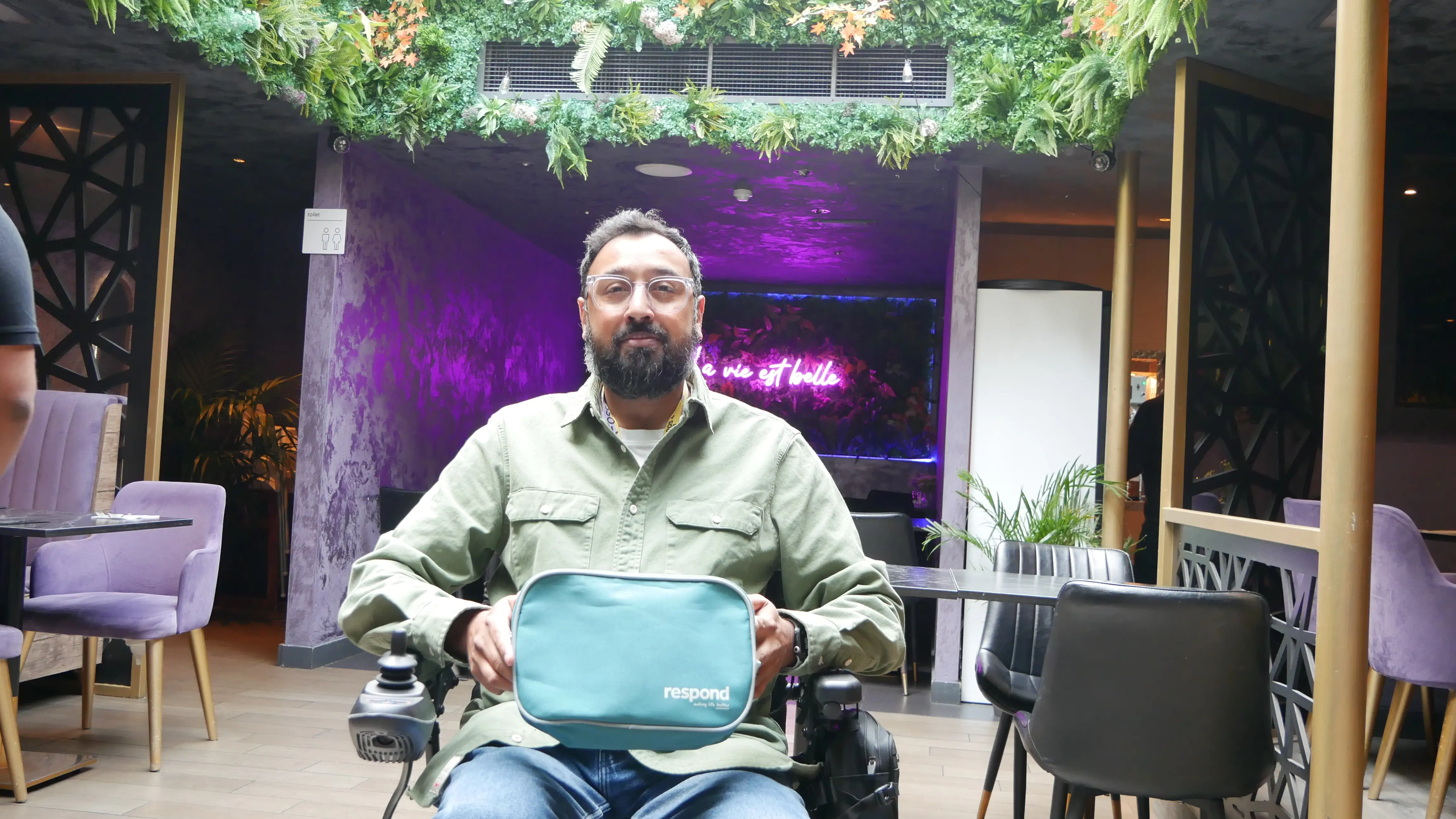 A man in a wheelchair smiles in a restaurant.