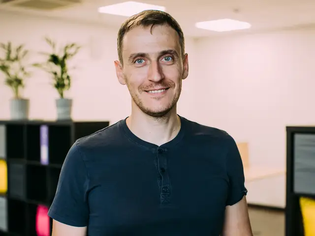 A man wearing a black T-shirt smiles.