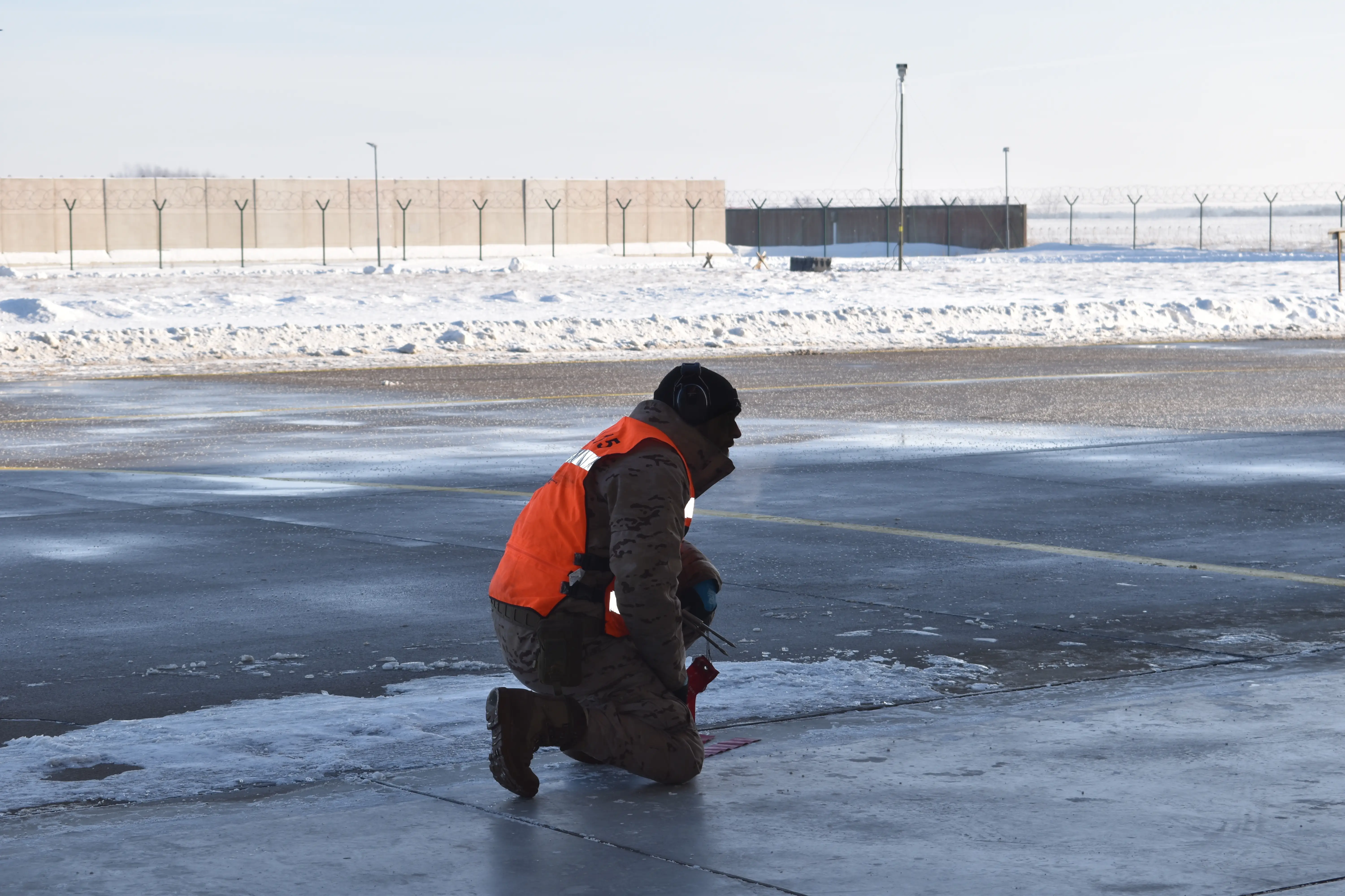 A member of Spain's 15th Wing kneels in a hangar at Šiauliai Air Base in Lithuania in January 2026.