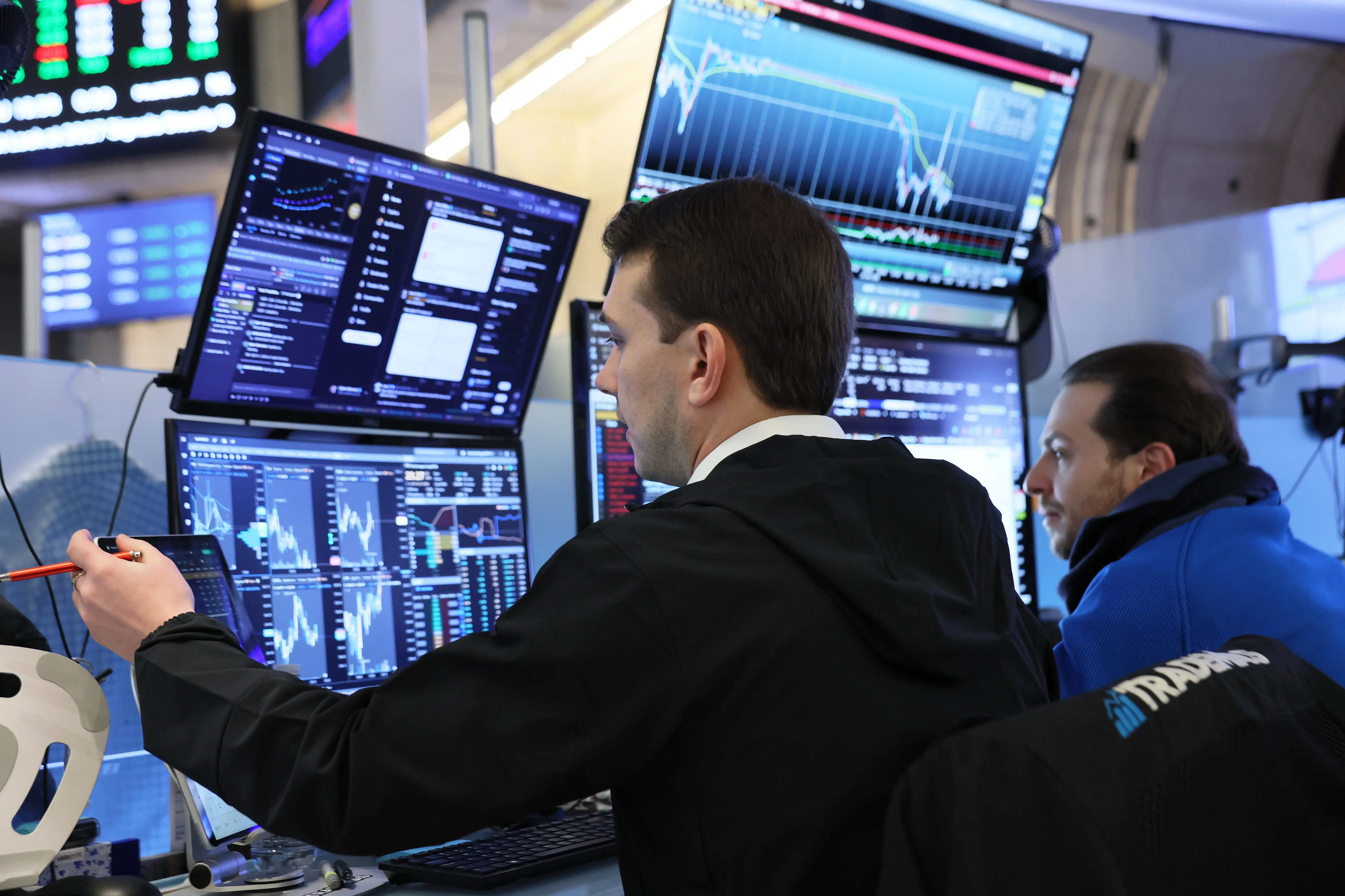 Traders sit in front of a computer screen