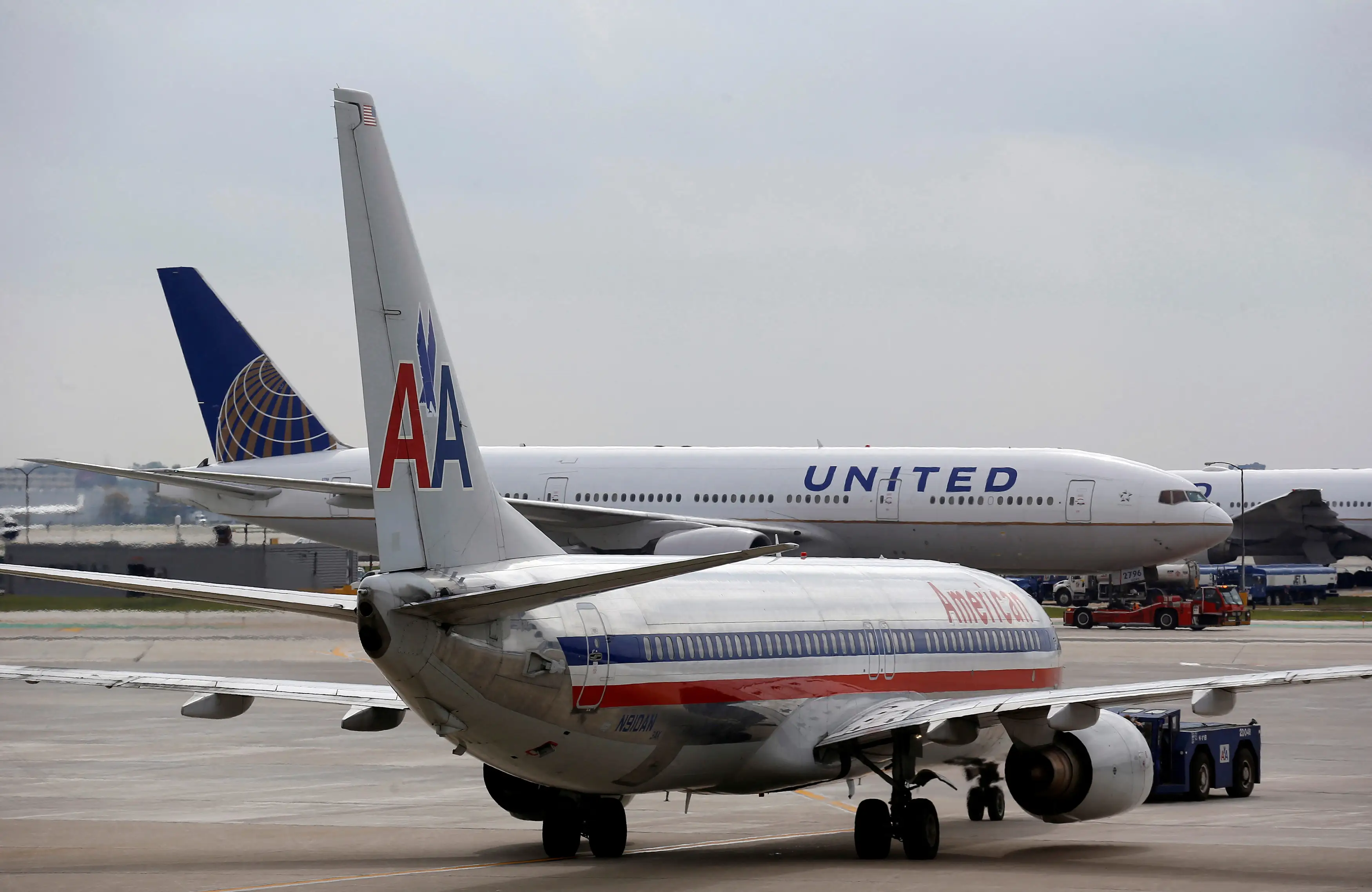 A United Airlines airplane passes by an American Airlines plane at O'Hare Airport in Chicago