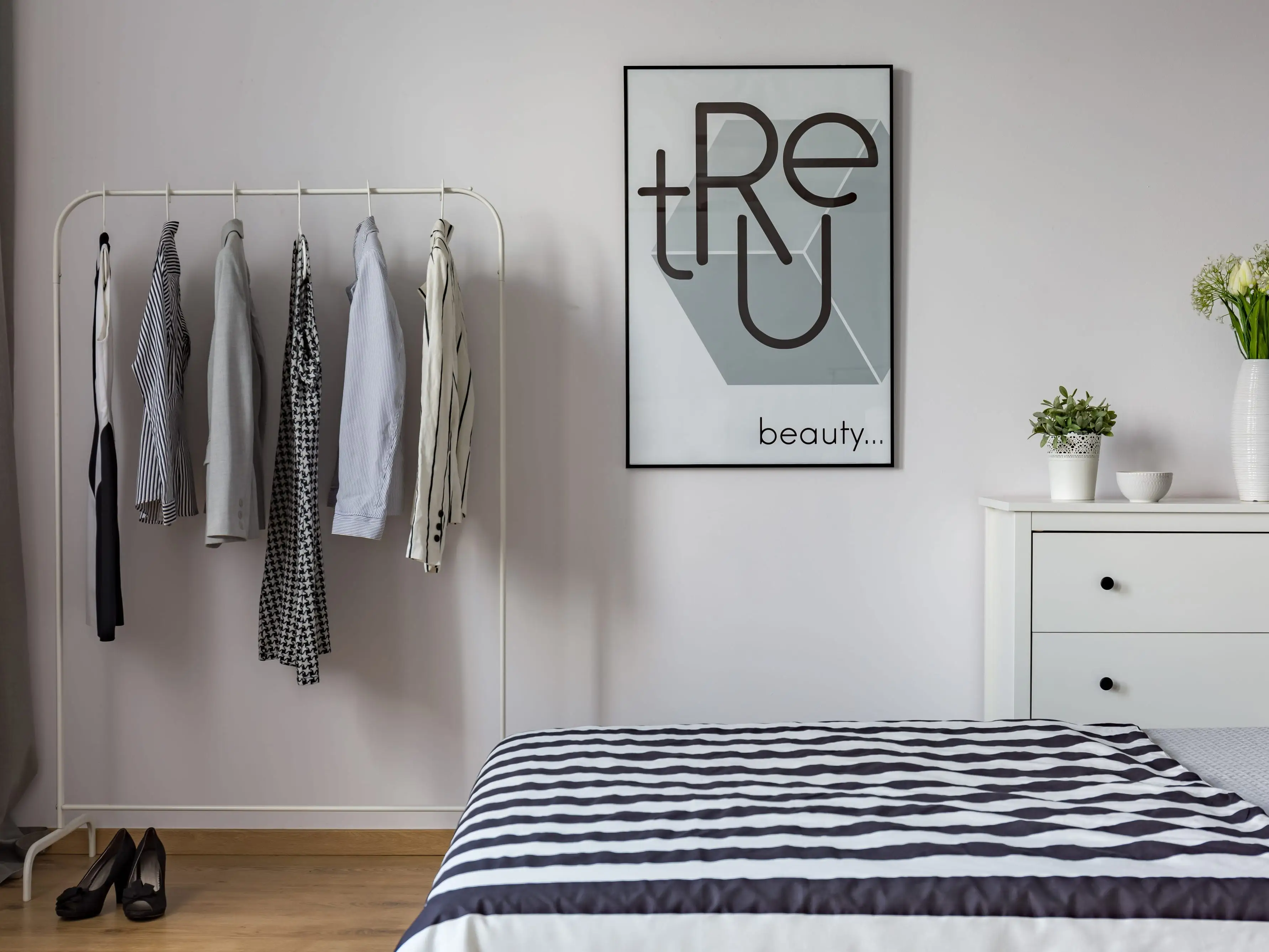 Clothing rack next to poster in bedroom