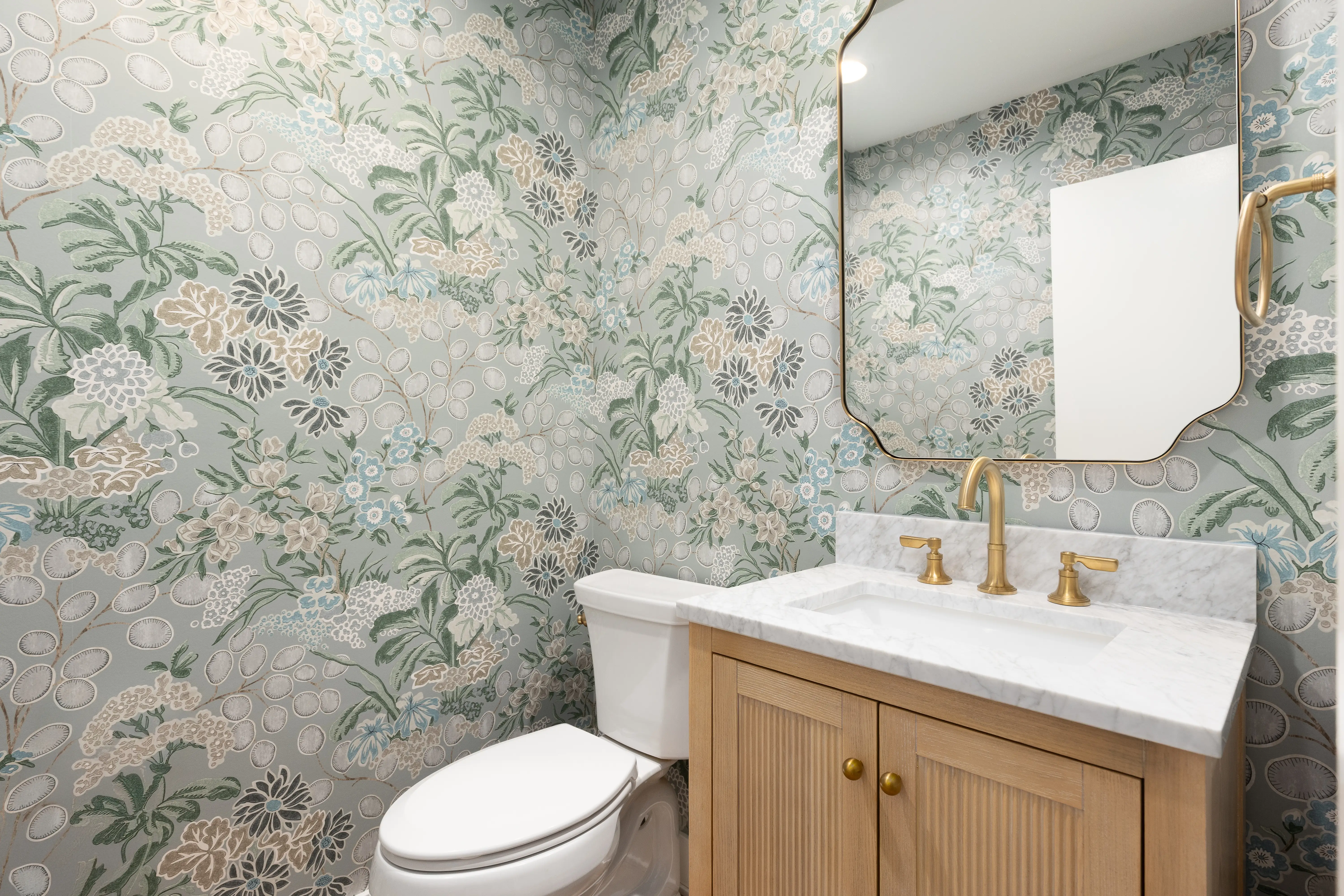Wallpaper bathroom with marble-top vanity with mirror above it
