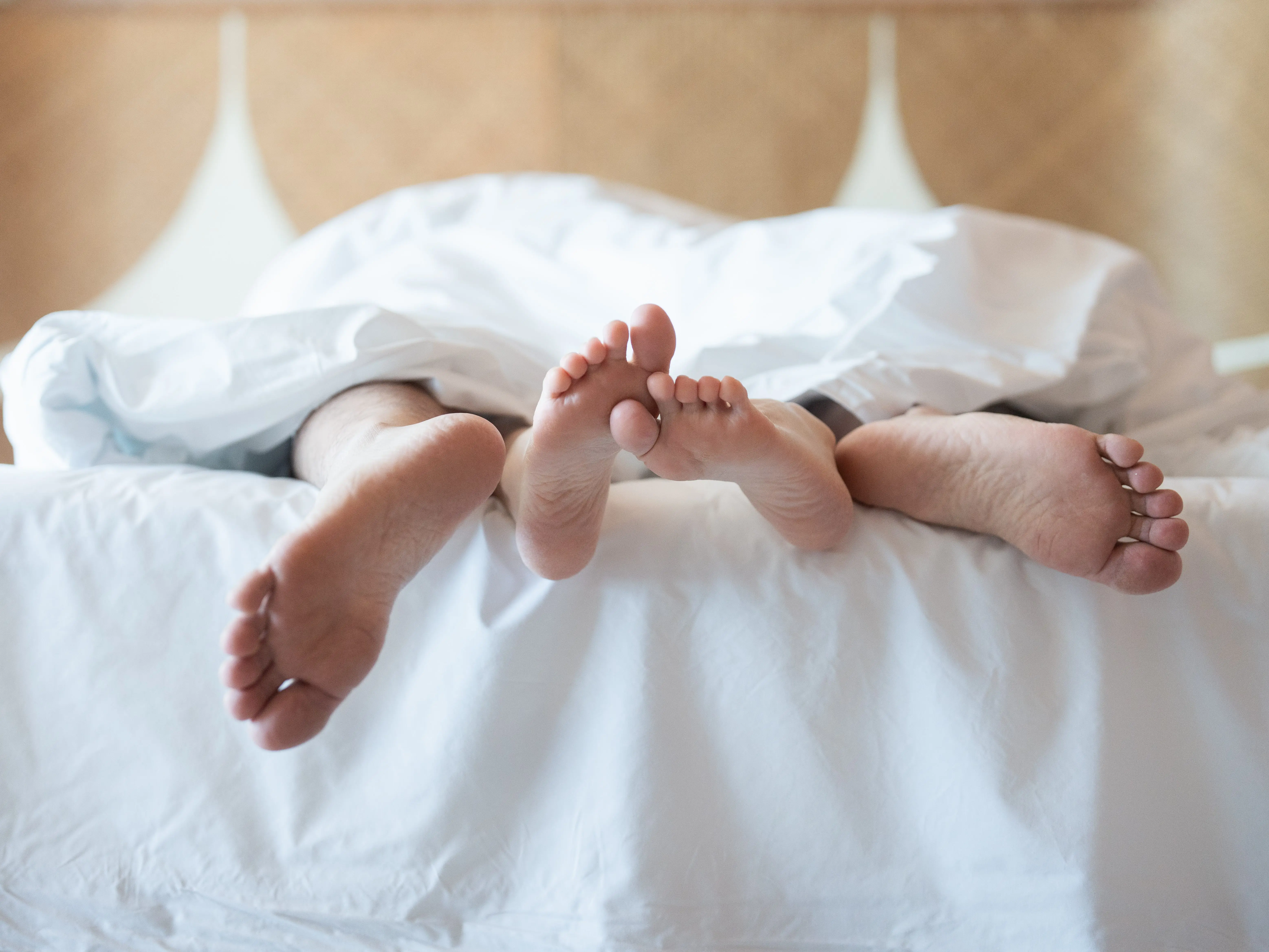 two people with their feet sticking out from under the sheets in bed