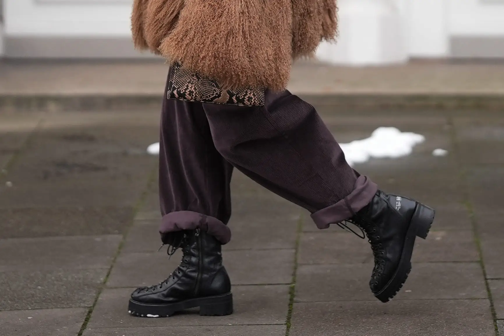 Person in fur jacket with rolled-up pants and platform boots walking