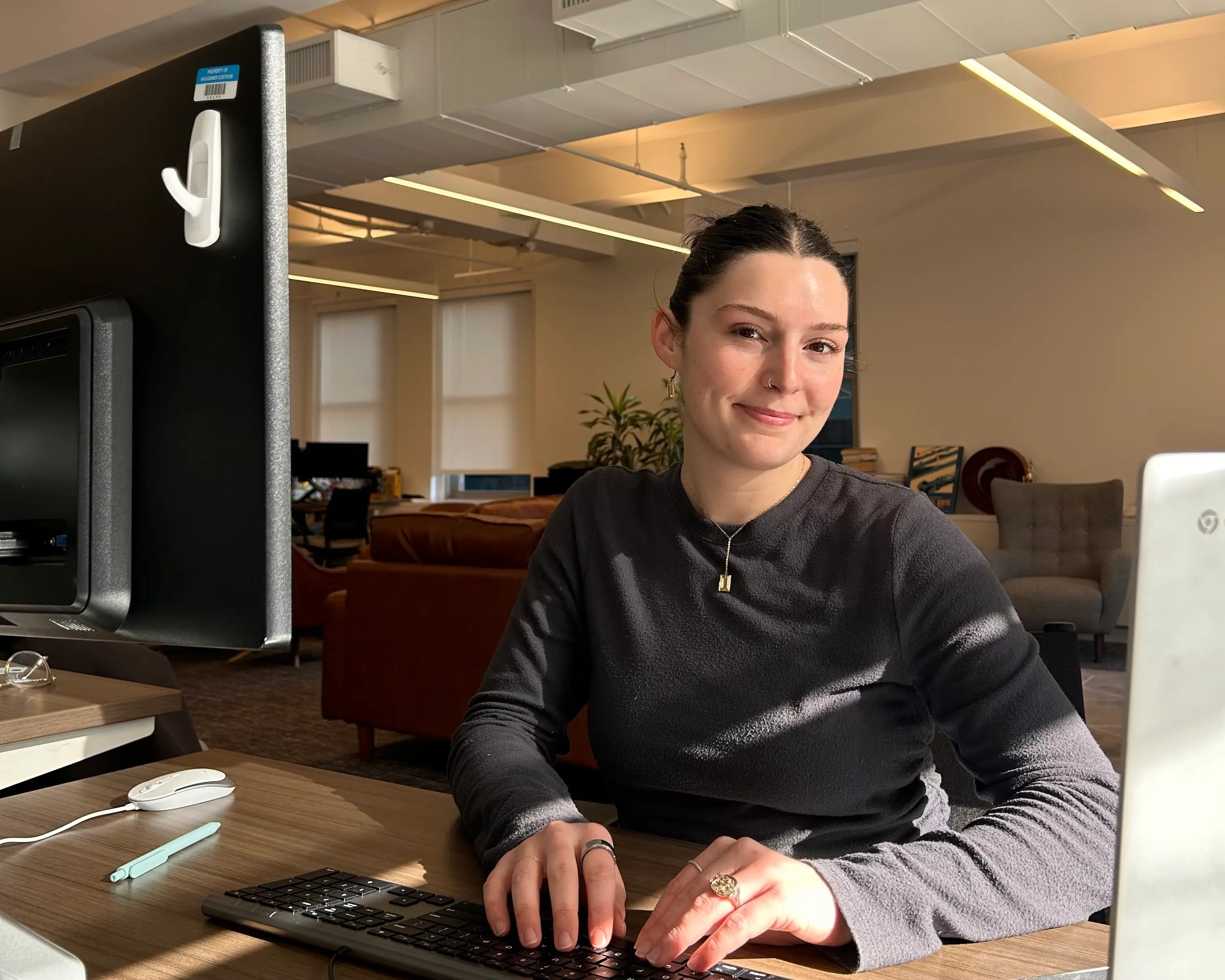 A young woman in an office types on a keyboard.