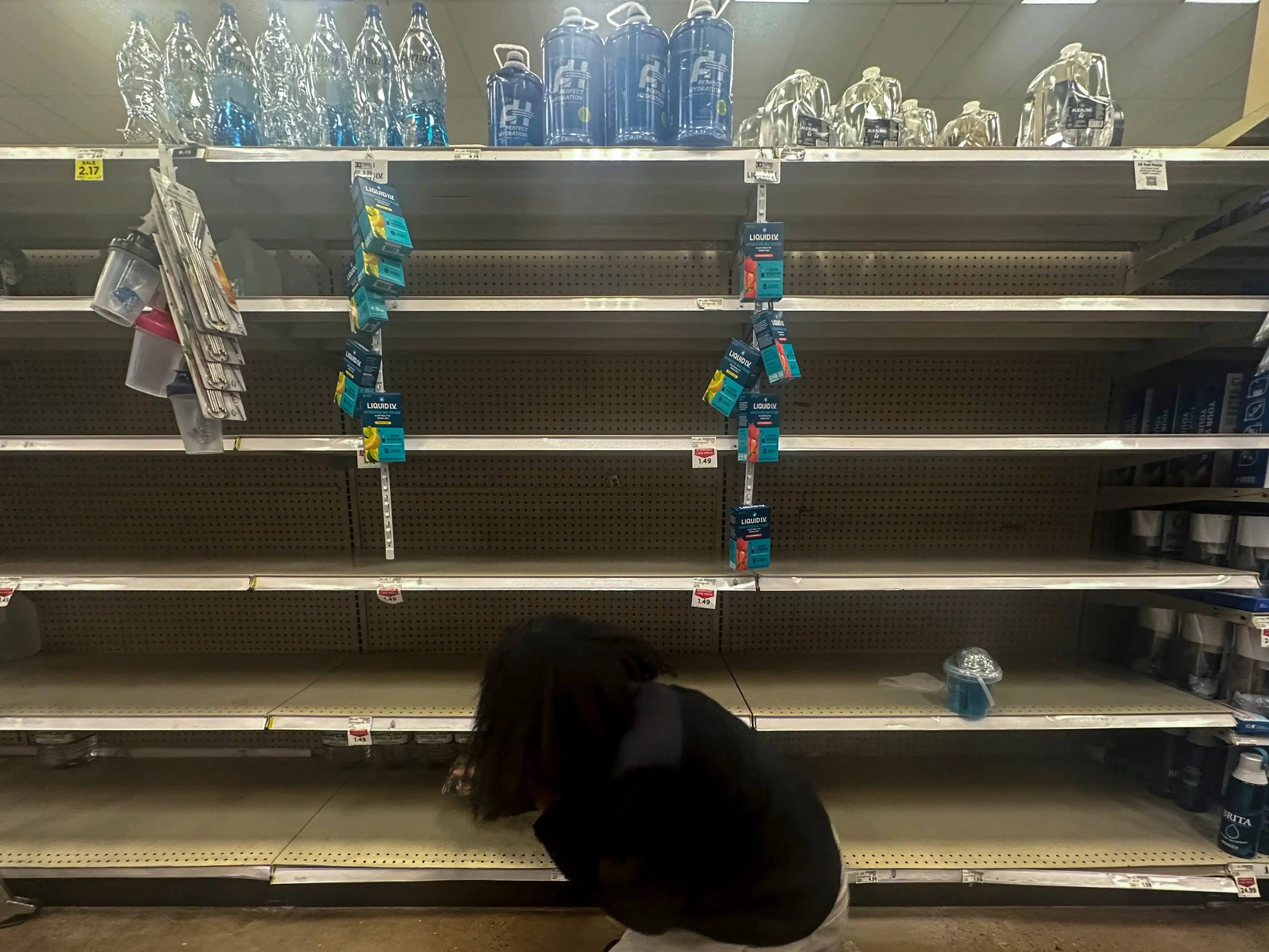 A shopper searches for water on near empty shelves in grocery store ahead of winter weather, Wednesday, Jan. 21, 2026, in Marietta, Ga.