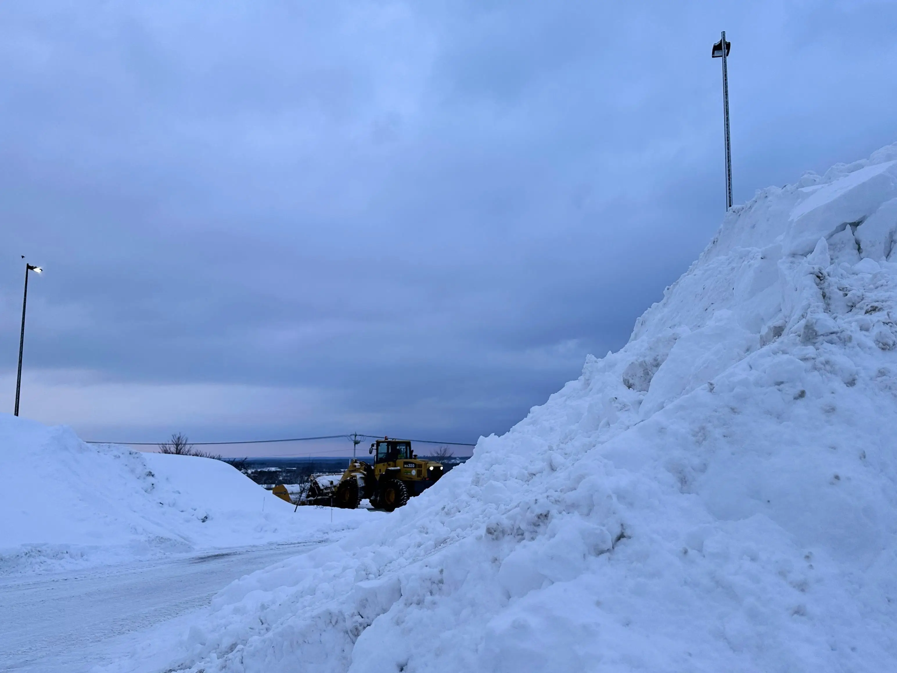 A snowplow works among piles of snow in Lowville, N.Y., on Thursday, Jan. 22, 2026.