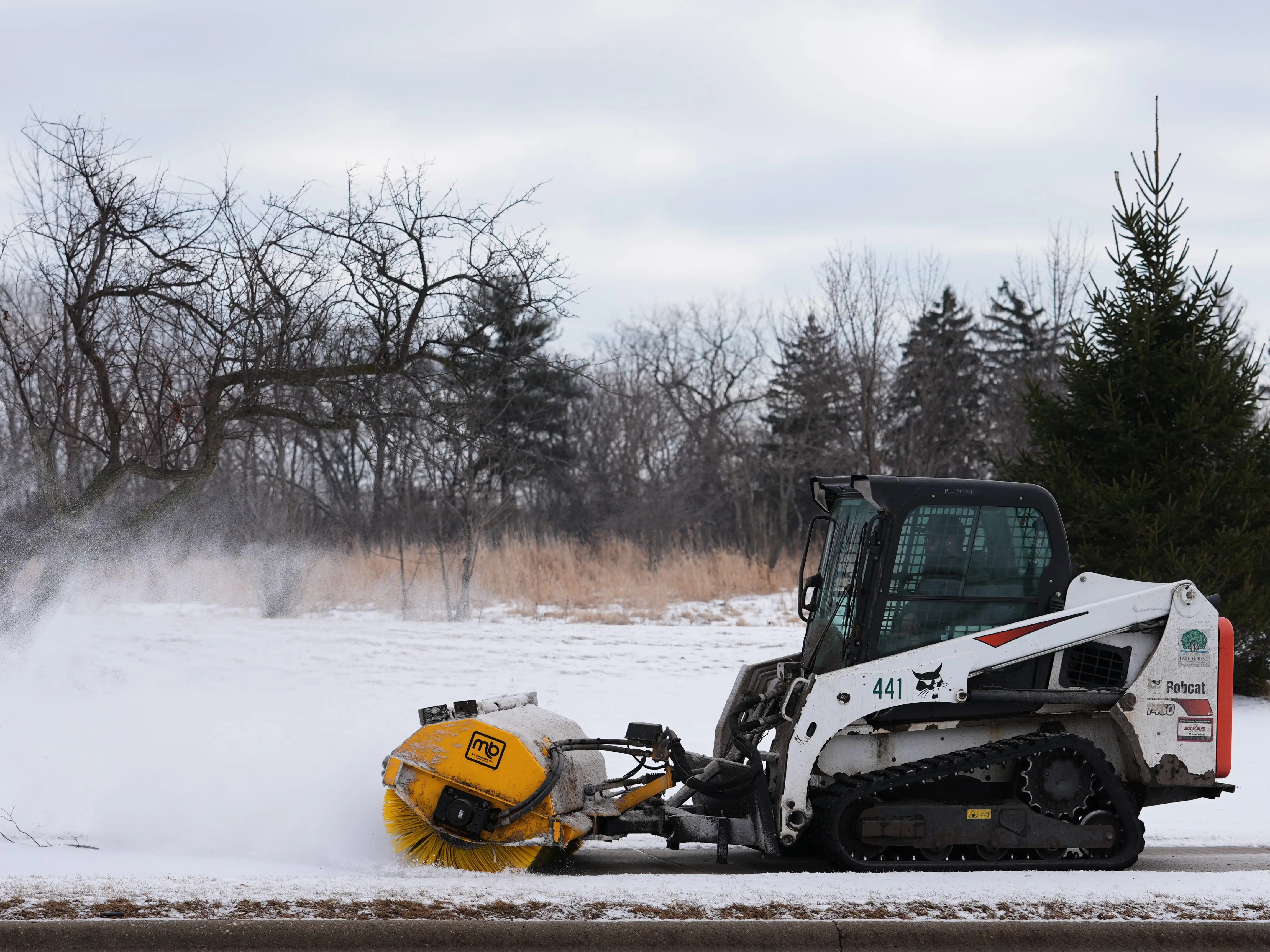 A plow clears snow from a snow-covered sidewalk during a cold day in Lake Forest, Ill., Wednesday, Jan. 21, 2026.