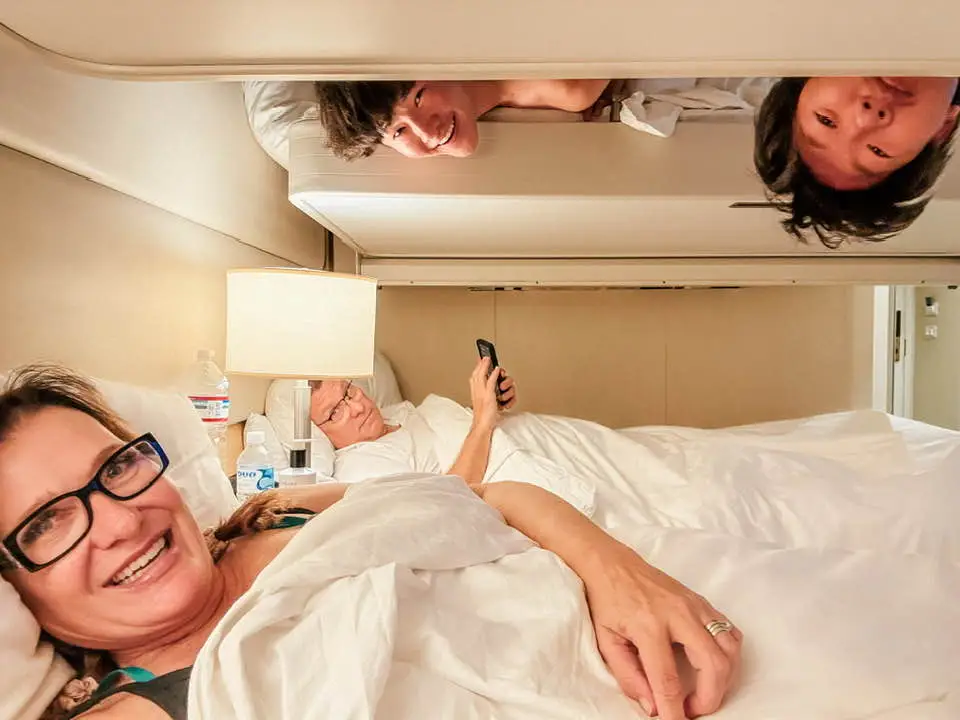 Author Jill Robbins in bed with husband in bed across from her and sons on bed above her on cruise