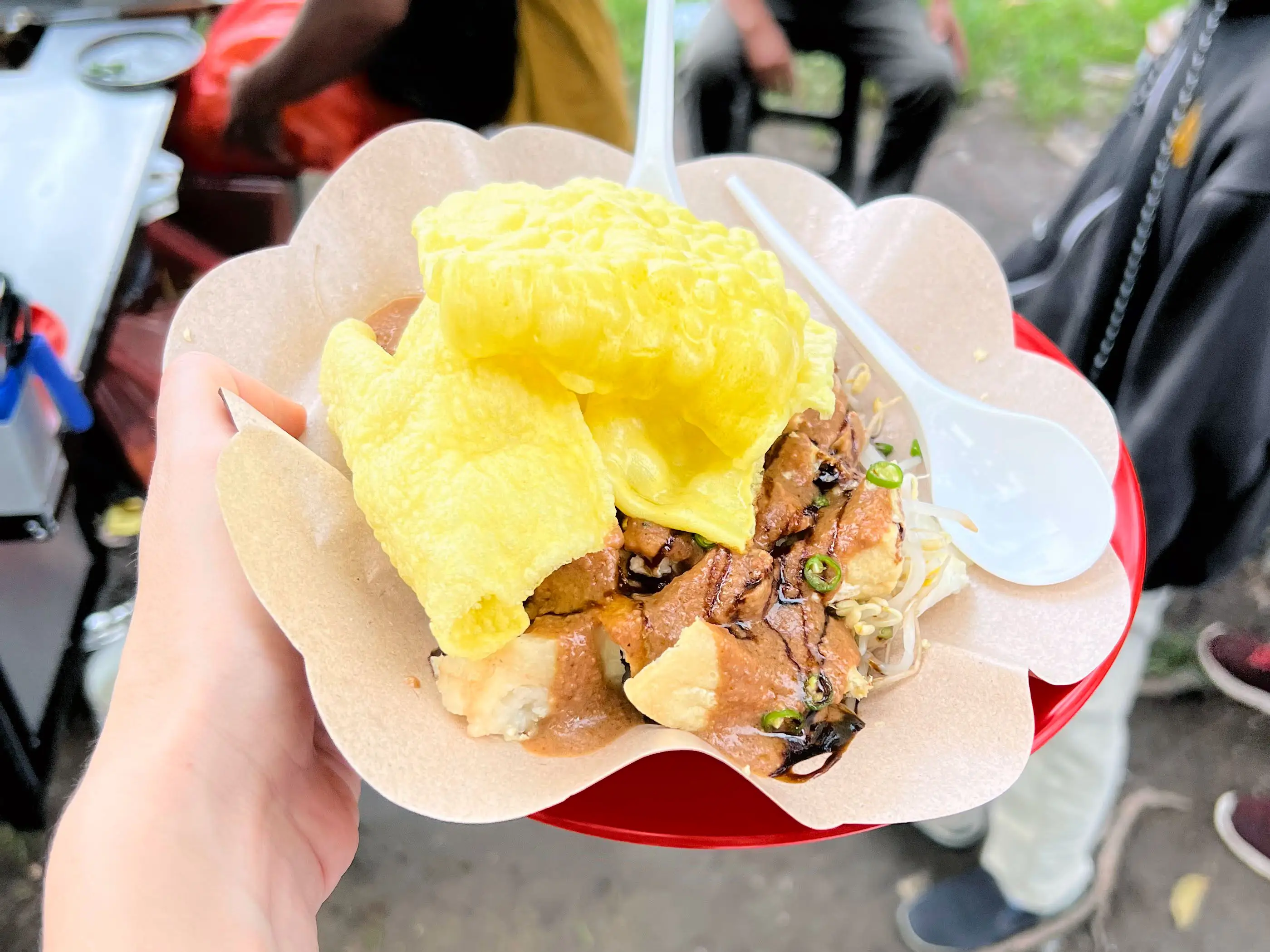 A plate of Tahu Tek, made with fried tofu, bean sprouts, peanut sauce, and a pile of crackers on top.