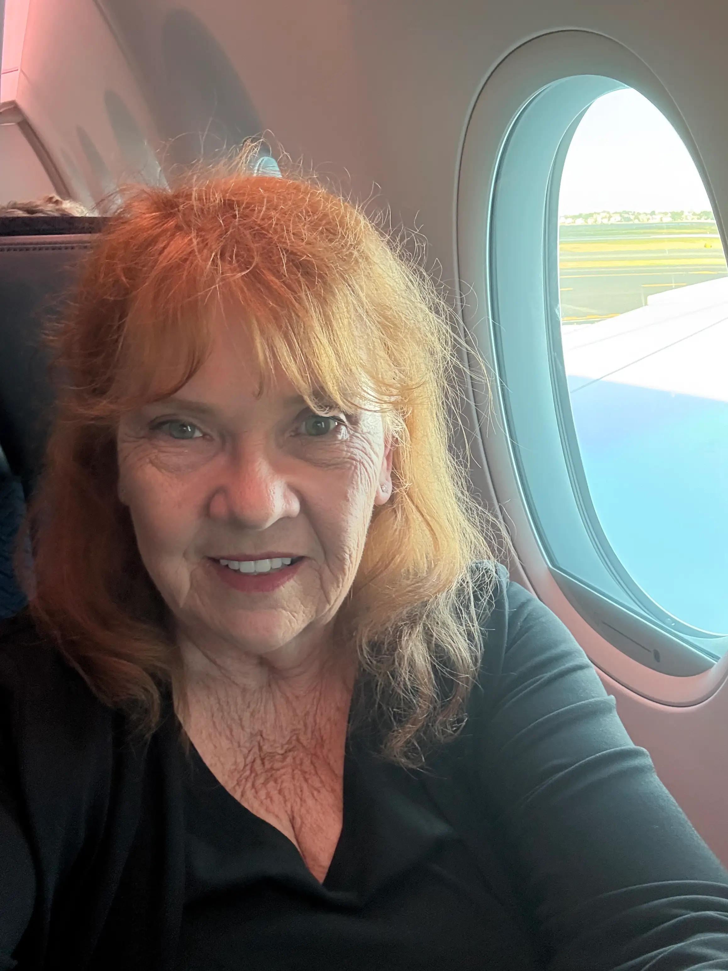 Sandy Adam sitting next to an airplane window.
