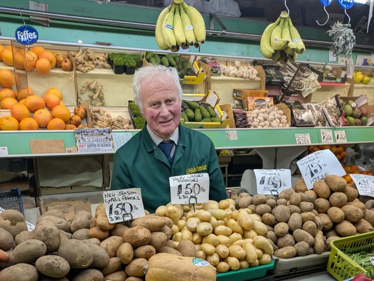 A greengrocer at his stand inside a market
