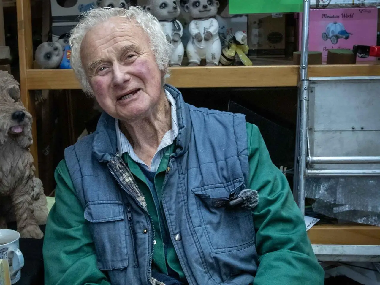 A senior sitting in front of garden ornaments.