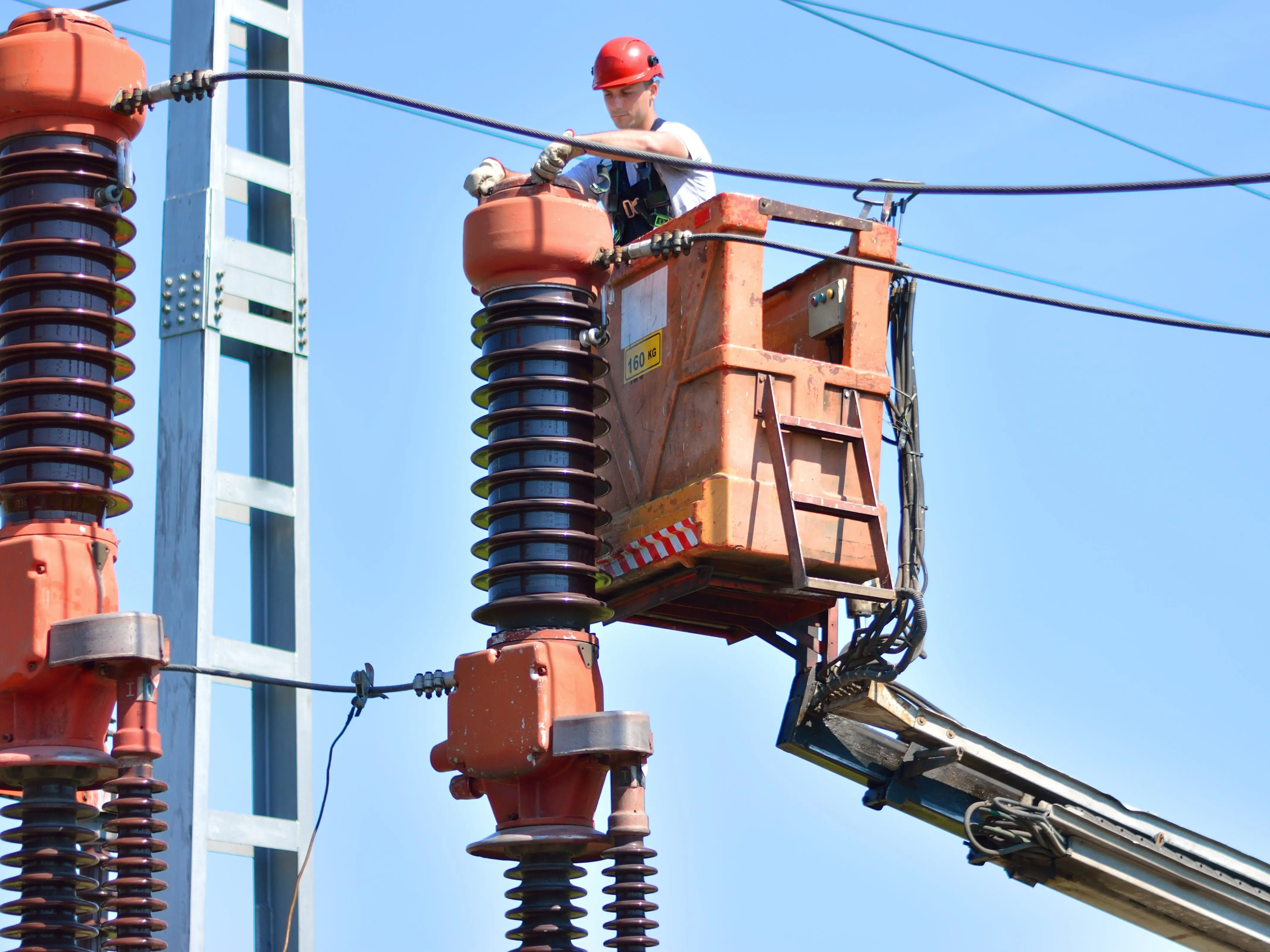 A worker with a hard hat is working in a power substation