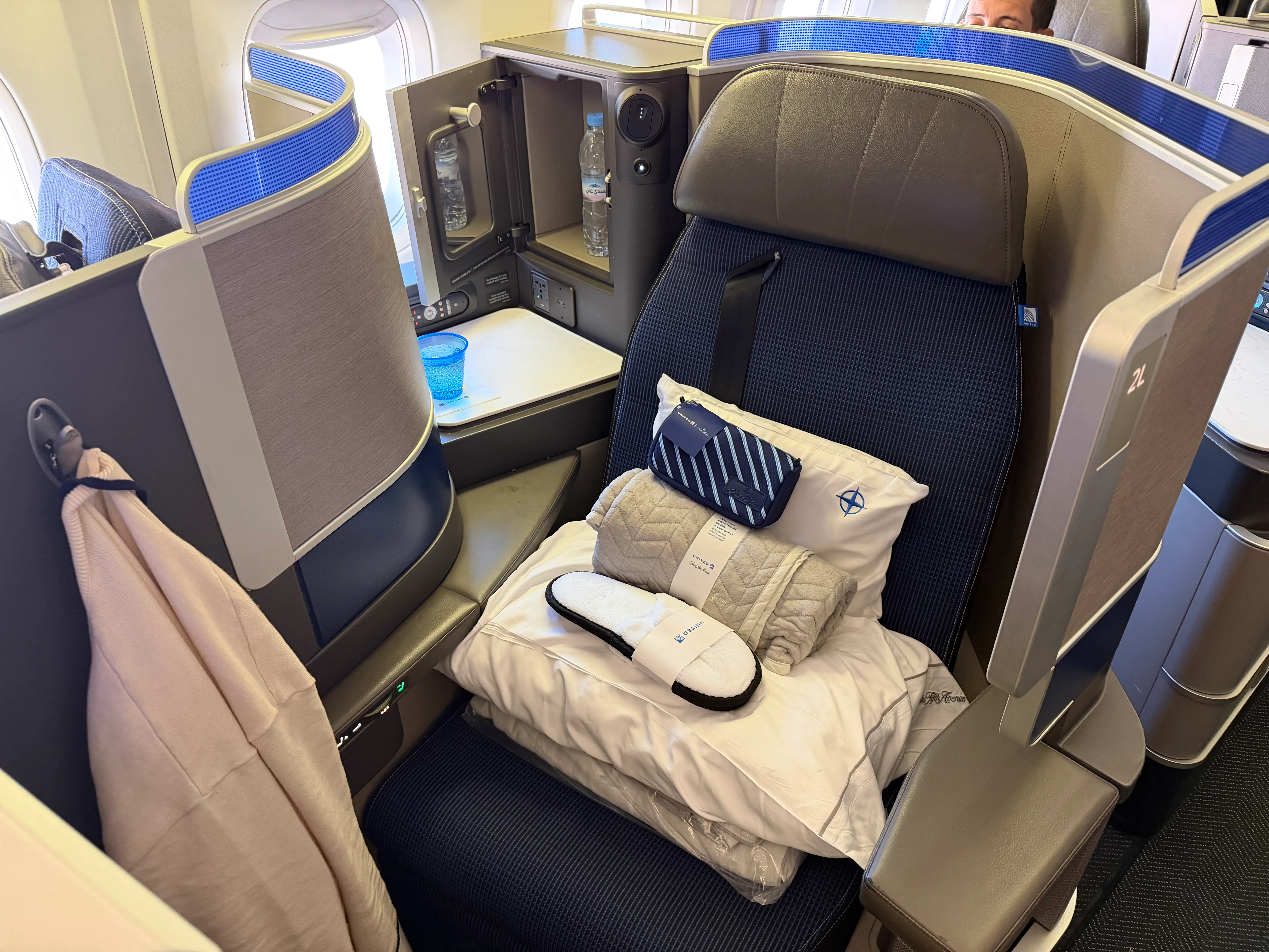 A private business-class seat, with slippers, a blanket, a pillow, and an amenity kit.