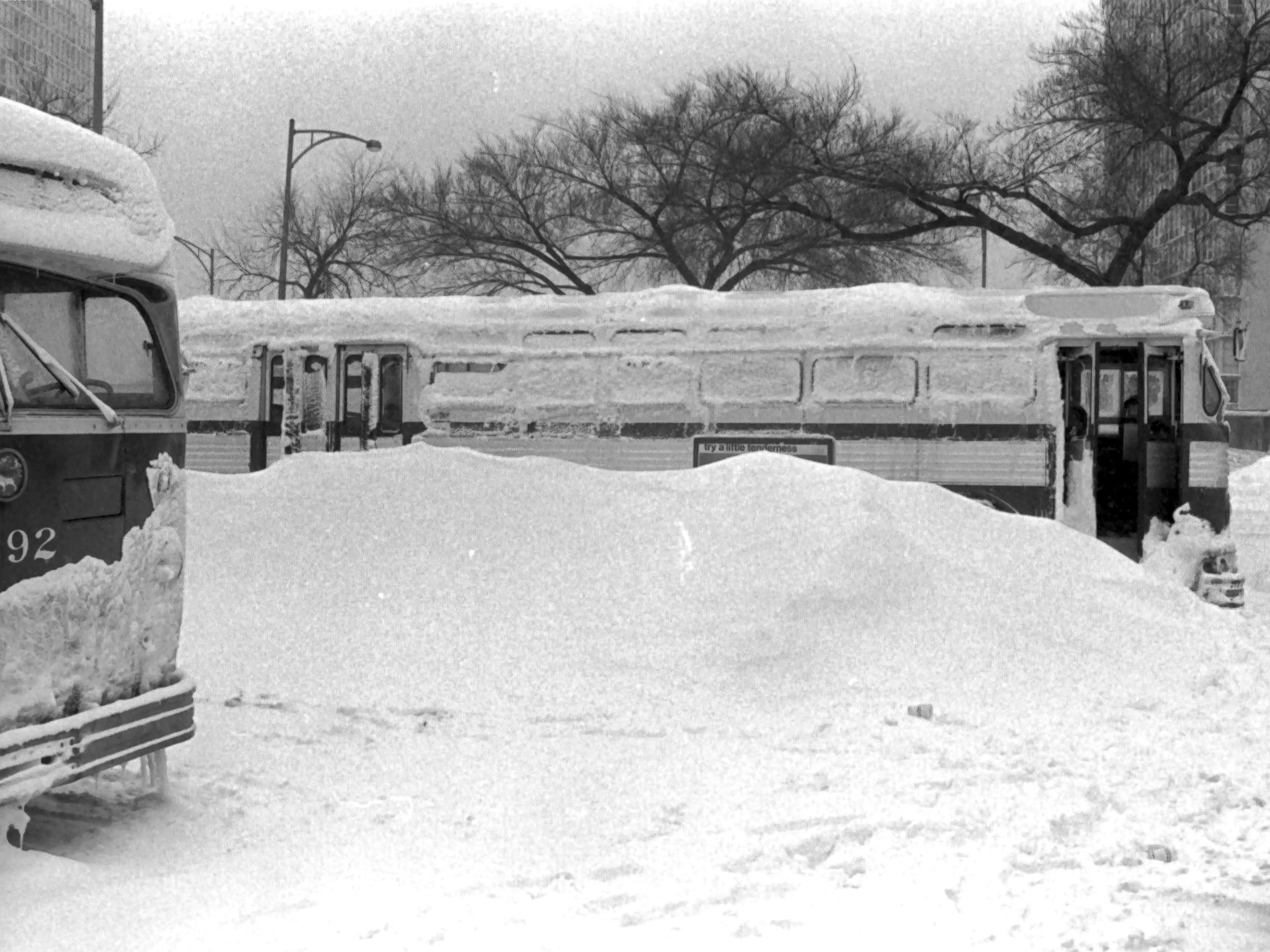 View of a Chicago Transit Authority (CTA) bus traveling its route during a winter blizzard in Chicago, IL, January 1967. Snow is piled high on the sidewalk.