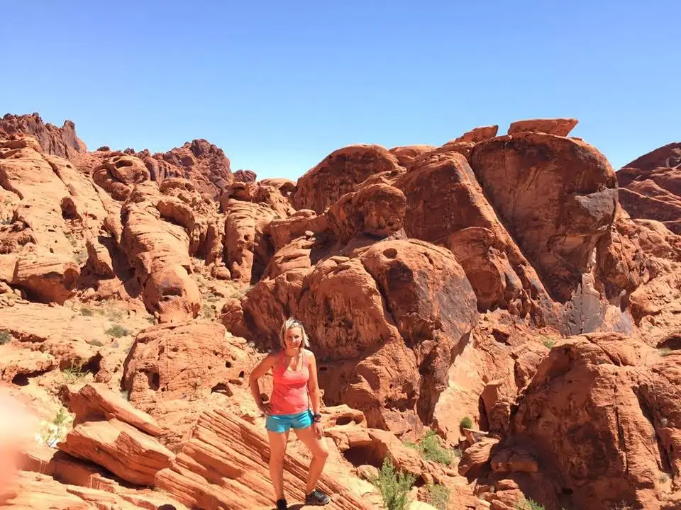 Author Erin Sanchez standing among red rocks in Valley of. Fire