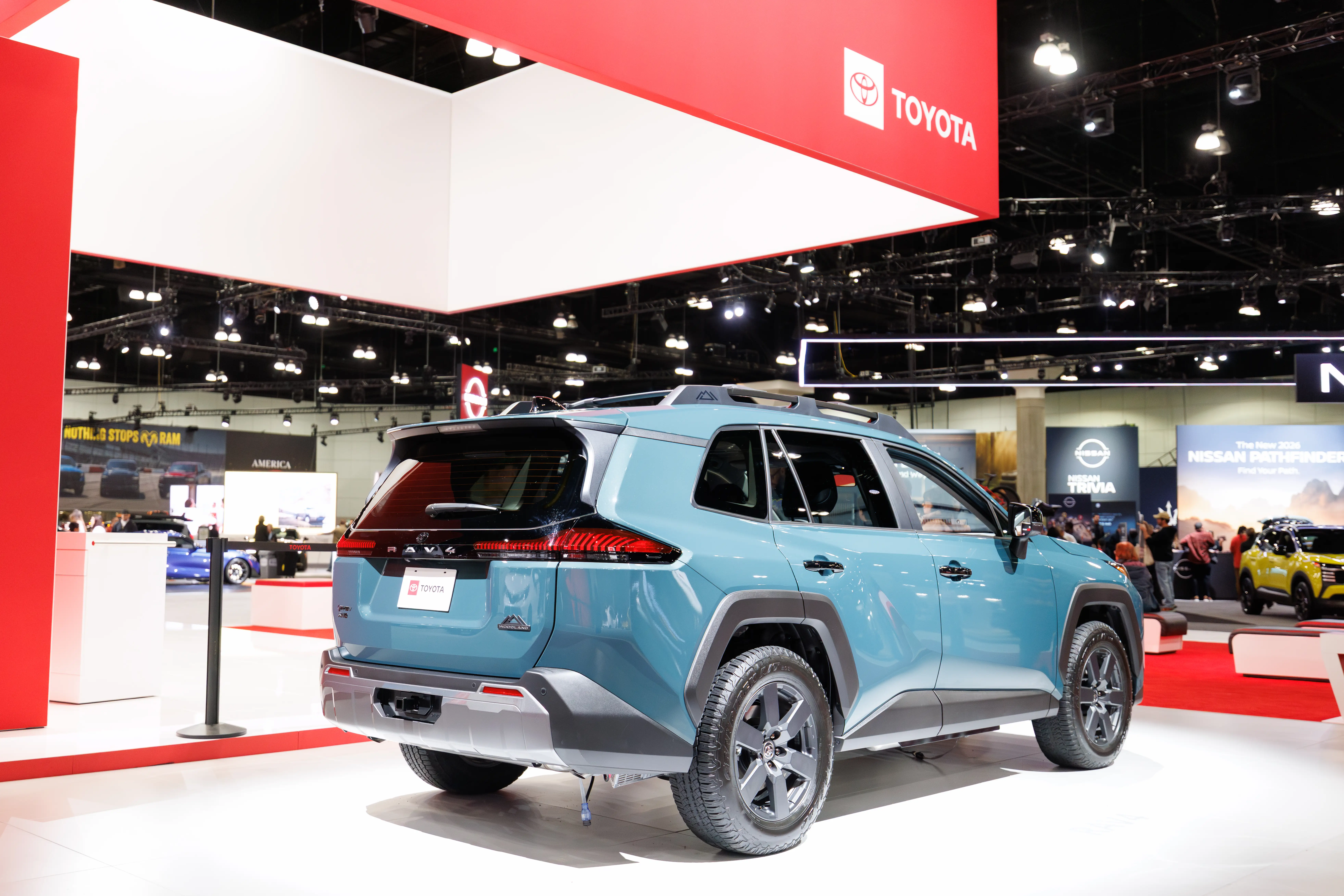 A blue 2026 Toyota RAV4 is displayed on a white tile floor during an auto show.