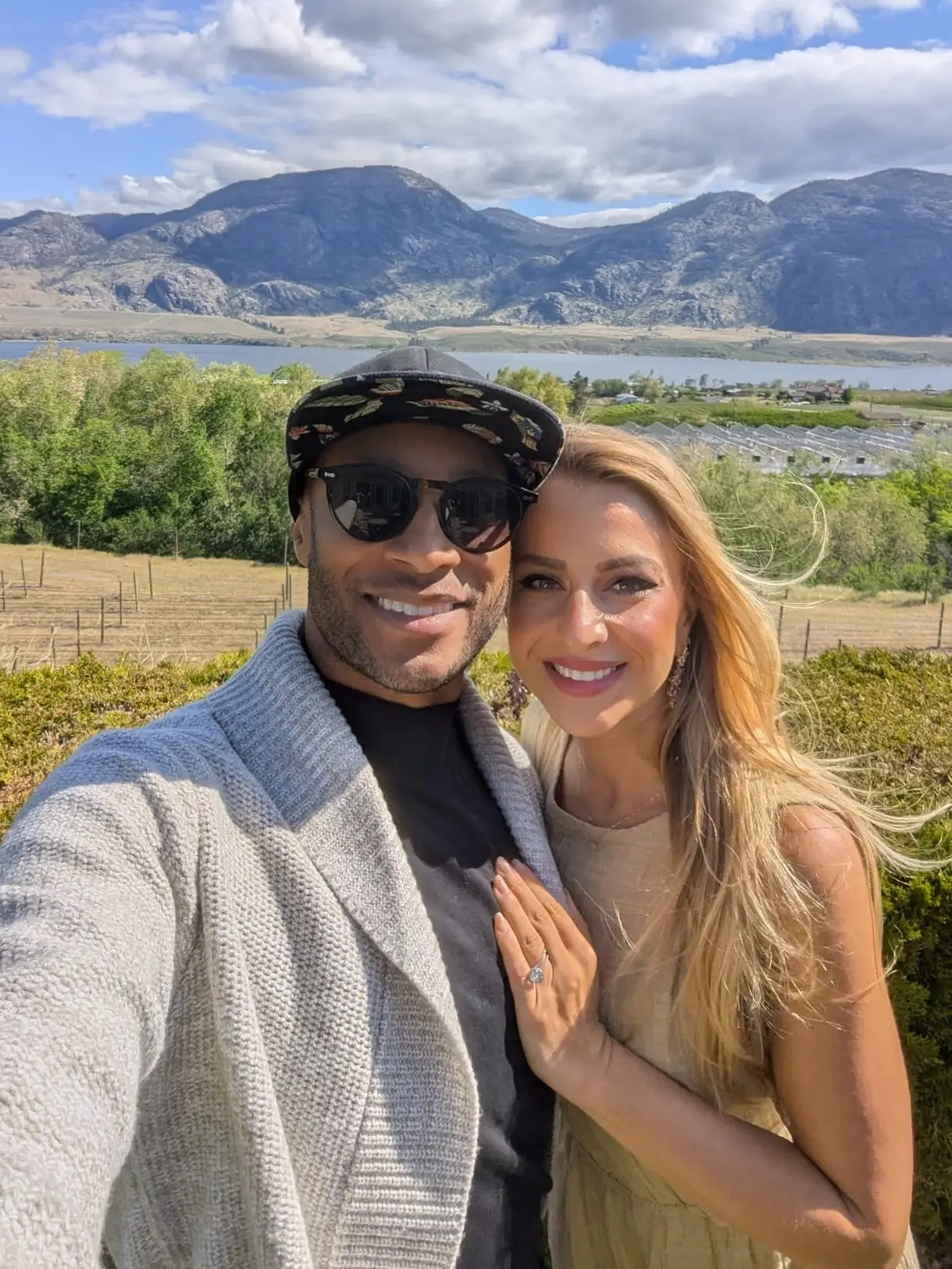 A man and a woman taking a selfie with a mountain range behind them.