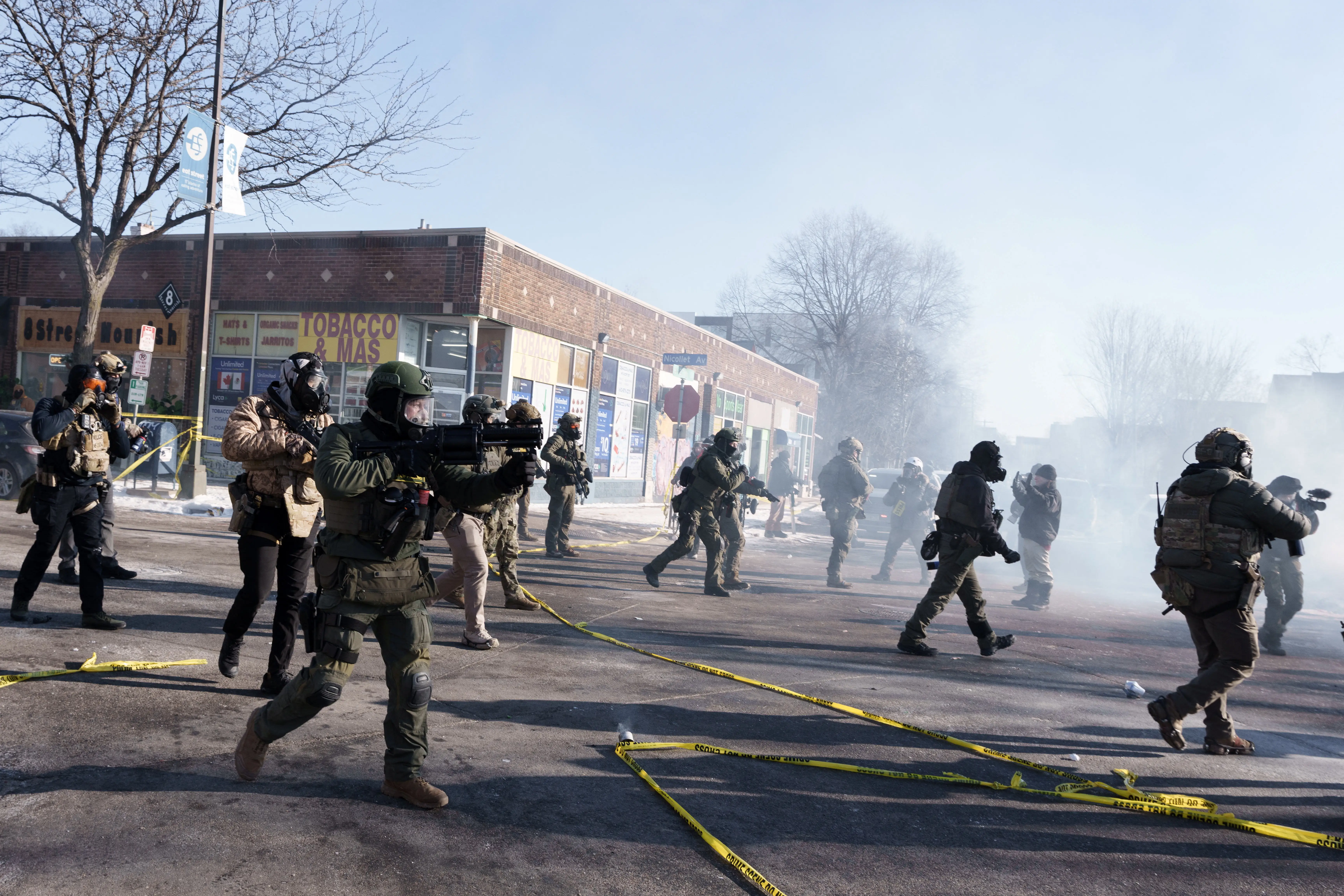 Federal agents run towards demonstrators and fire munitions on a city street.