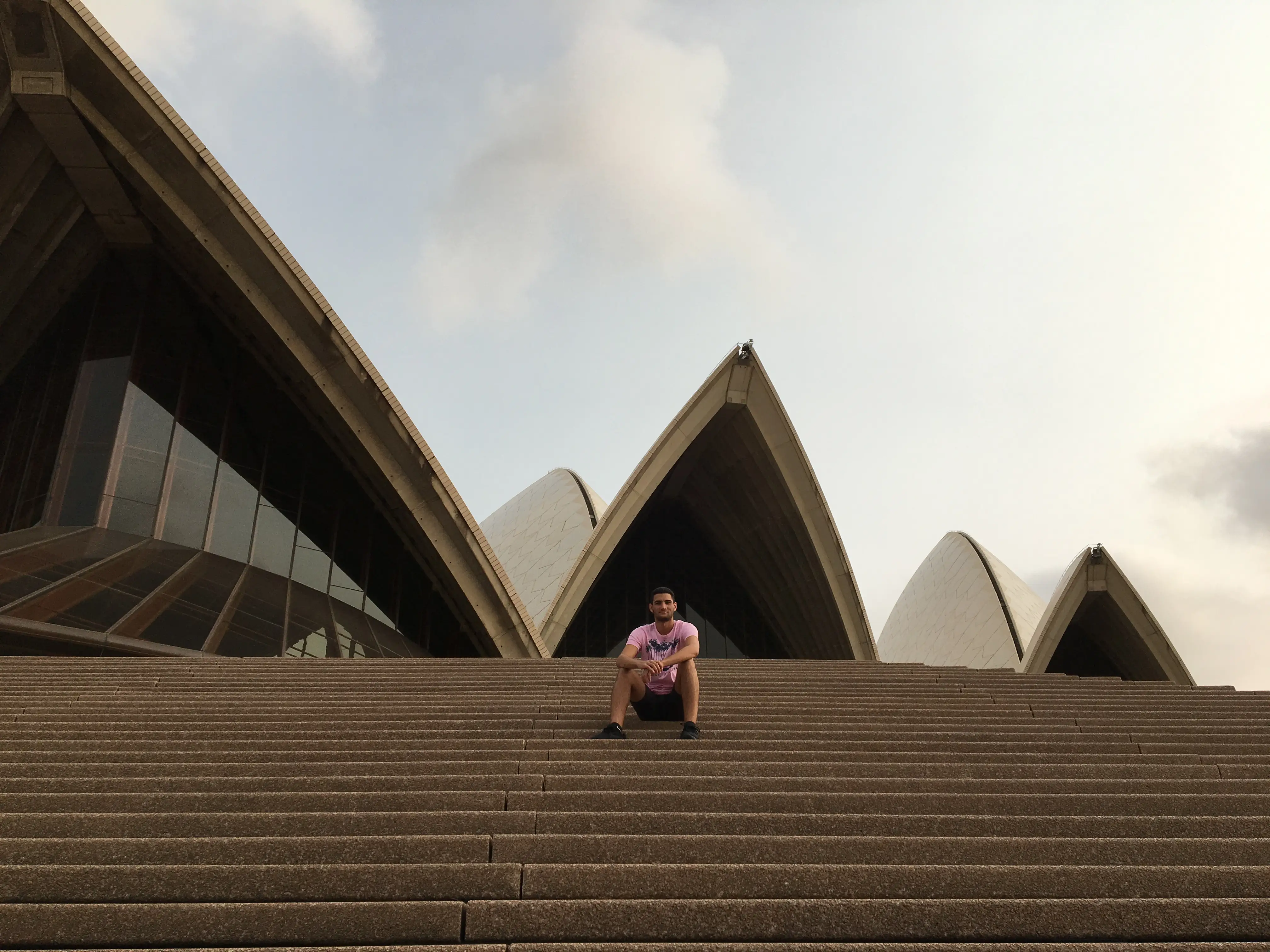 Sitting on the steps outside the Sydney Opera House in Australia.