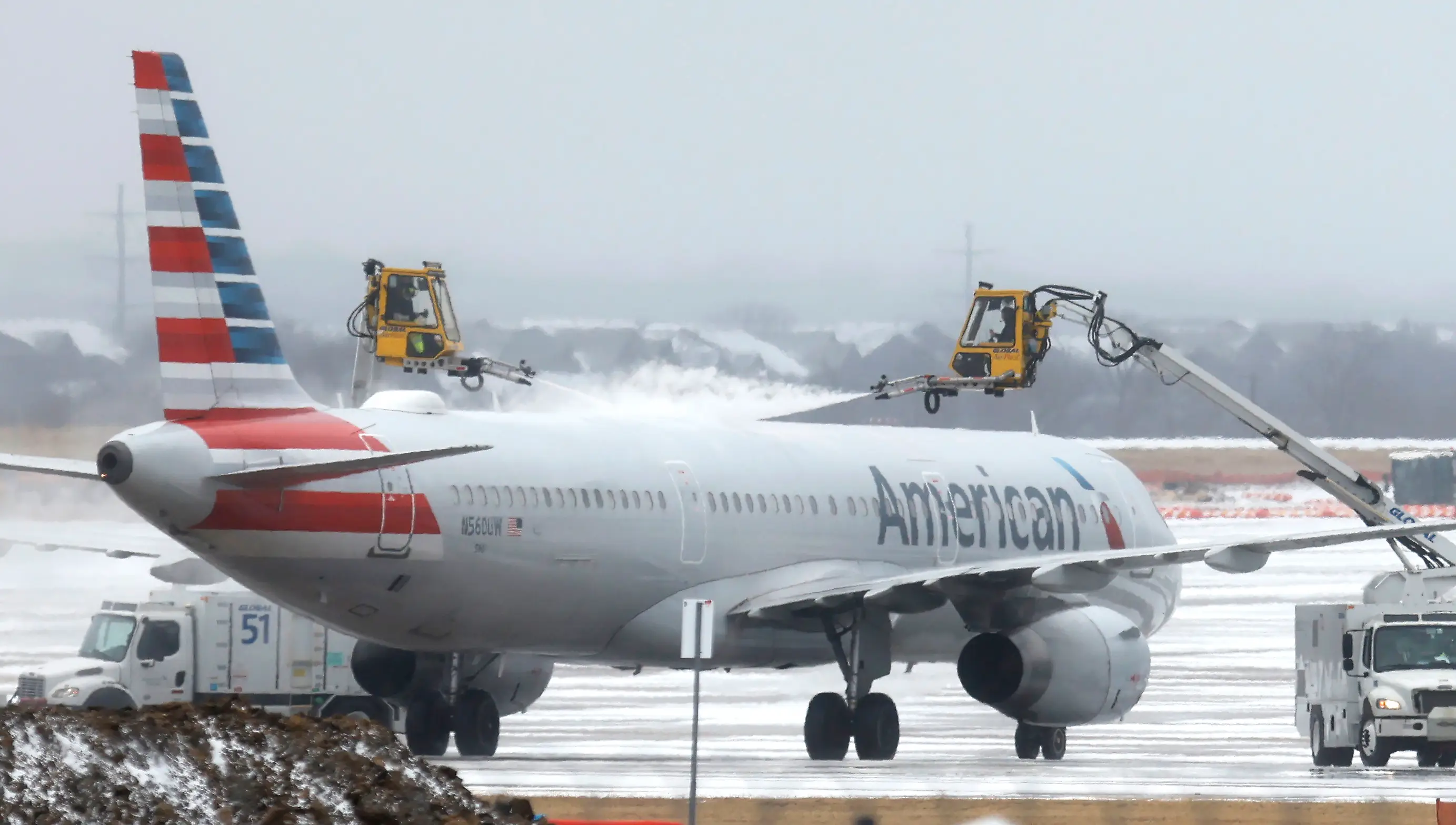 Ground crews de-ice an American Airlines jet at Dallas Fort Worth International Airport on January 24, 2026 in Dallas, Texas.