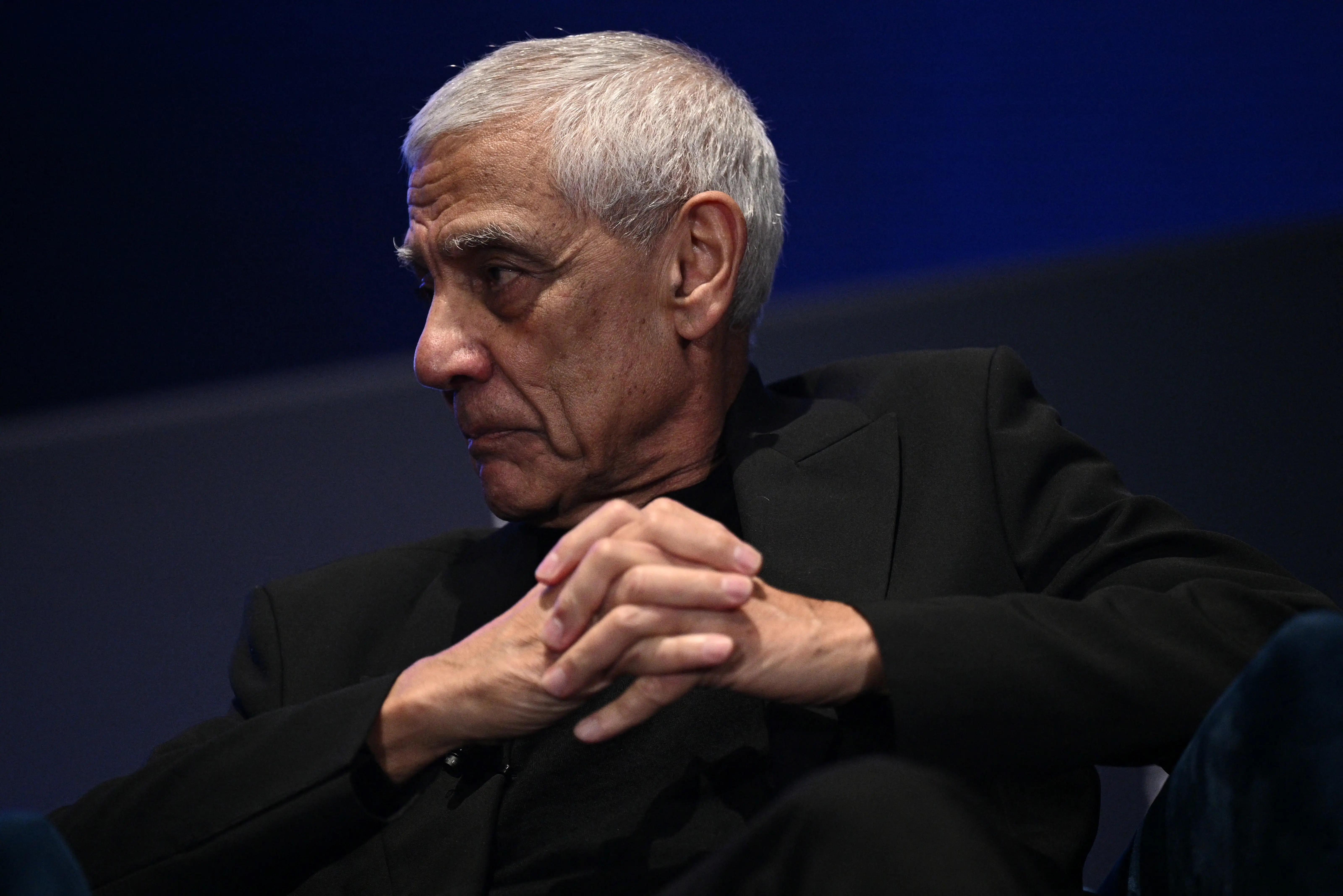 Khosla Ventures founder Vinod Khosla clasps his hands together while listening to someone speak during a panel.