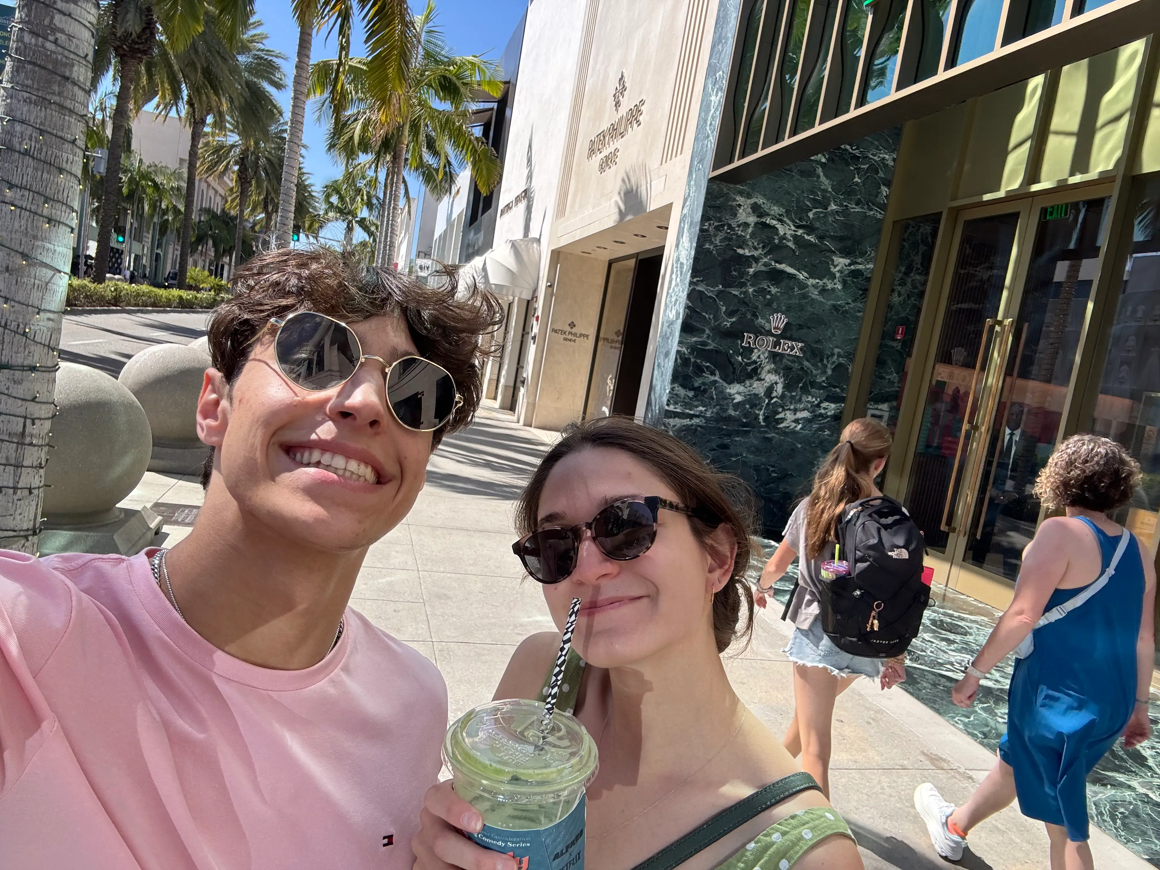 Anna, holding a matcha drink, poses with her brother on Rodeo Drive.