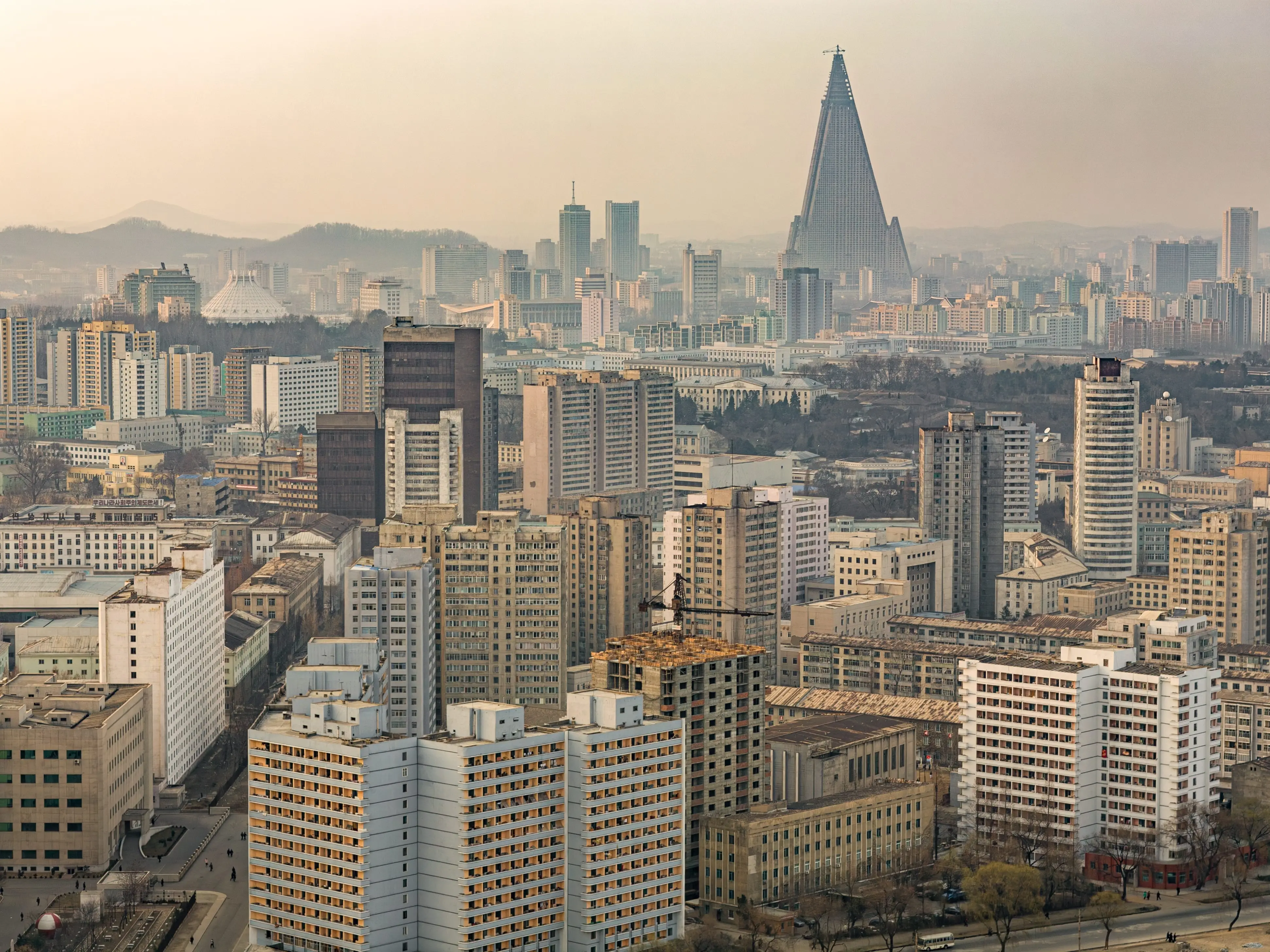 PYONGYANG, NORTH KOREA, MARCH 26, 2008: general view of  city skyline from Yanggakdo International Hotel, with massive pyramidal silhouette of Ryugyong hotel and Ice Rink to the left