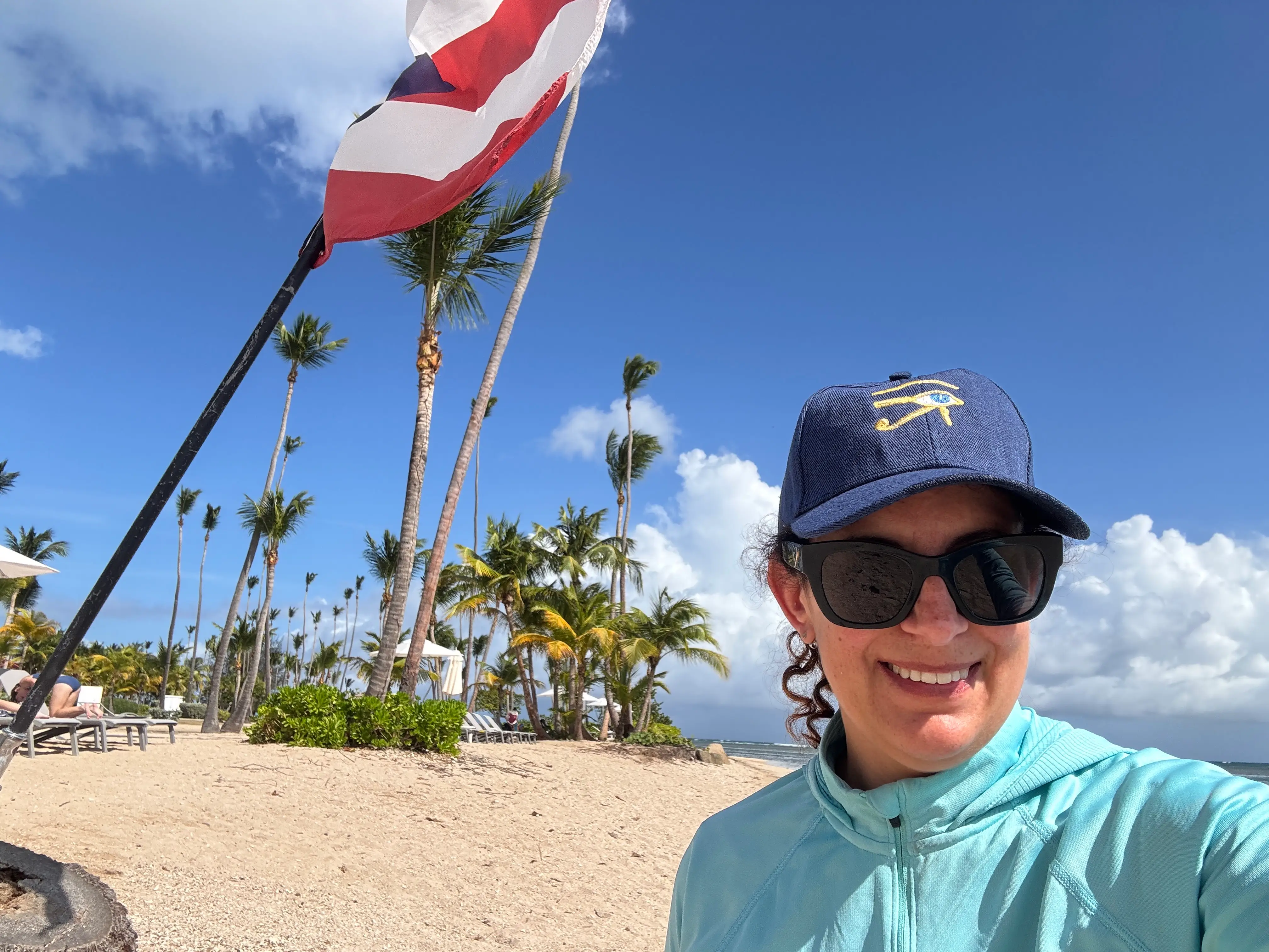 Author Jamie Davis Smith smiling on beach with Puerto Rico flag in background
