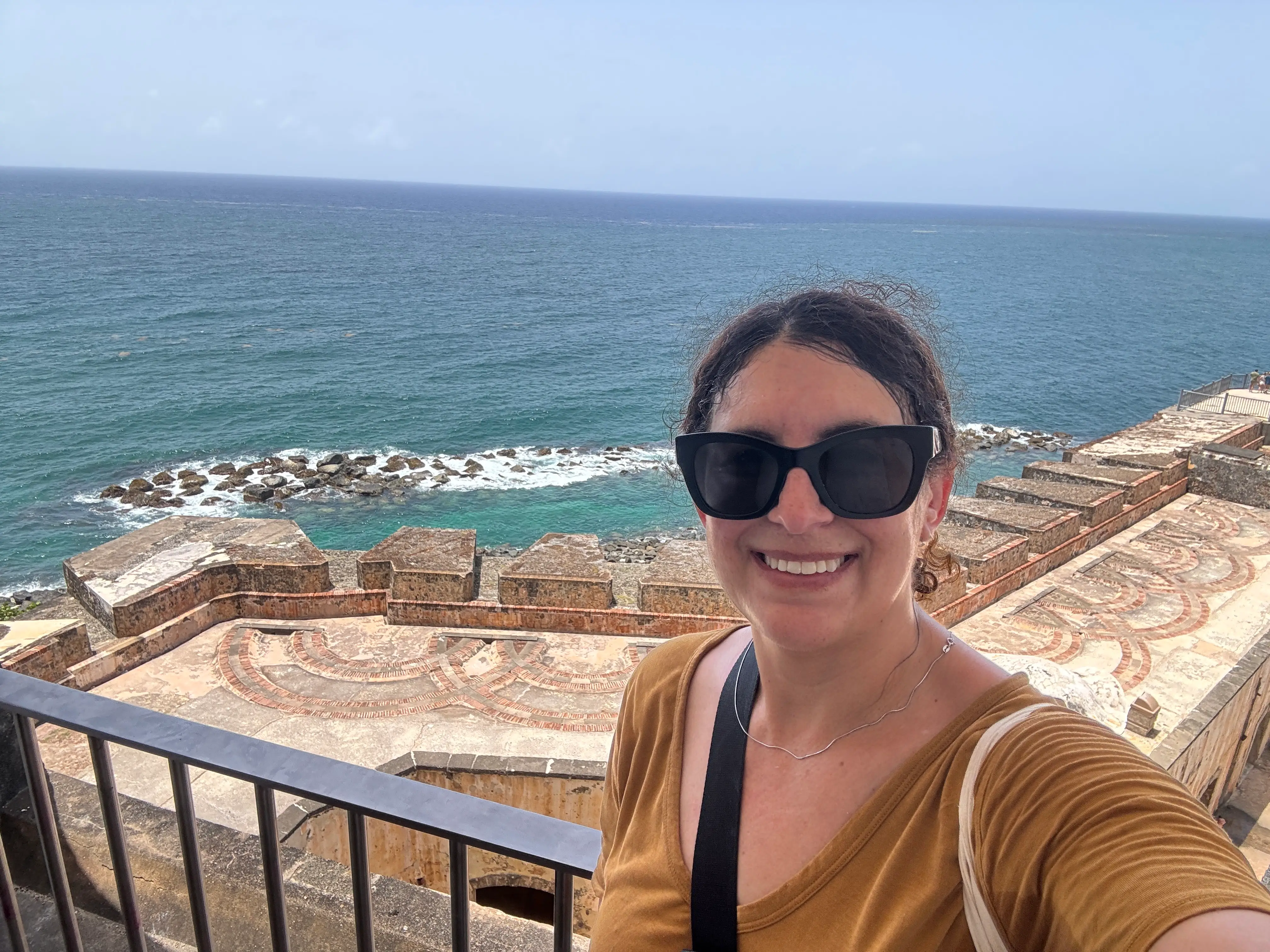 Author Jamie Davis Smith smiling on balcony with view of beach behind her