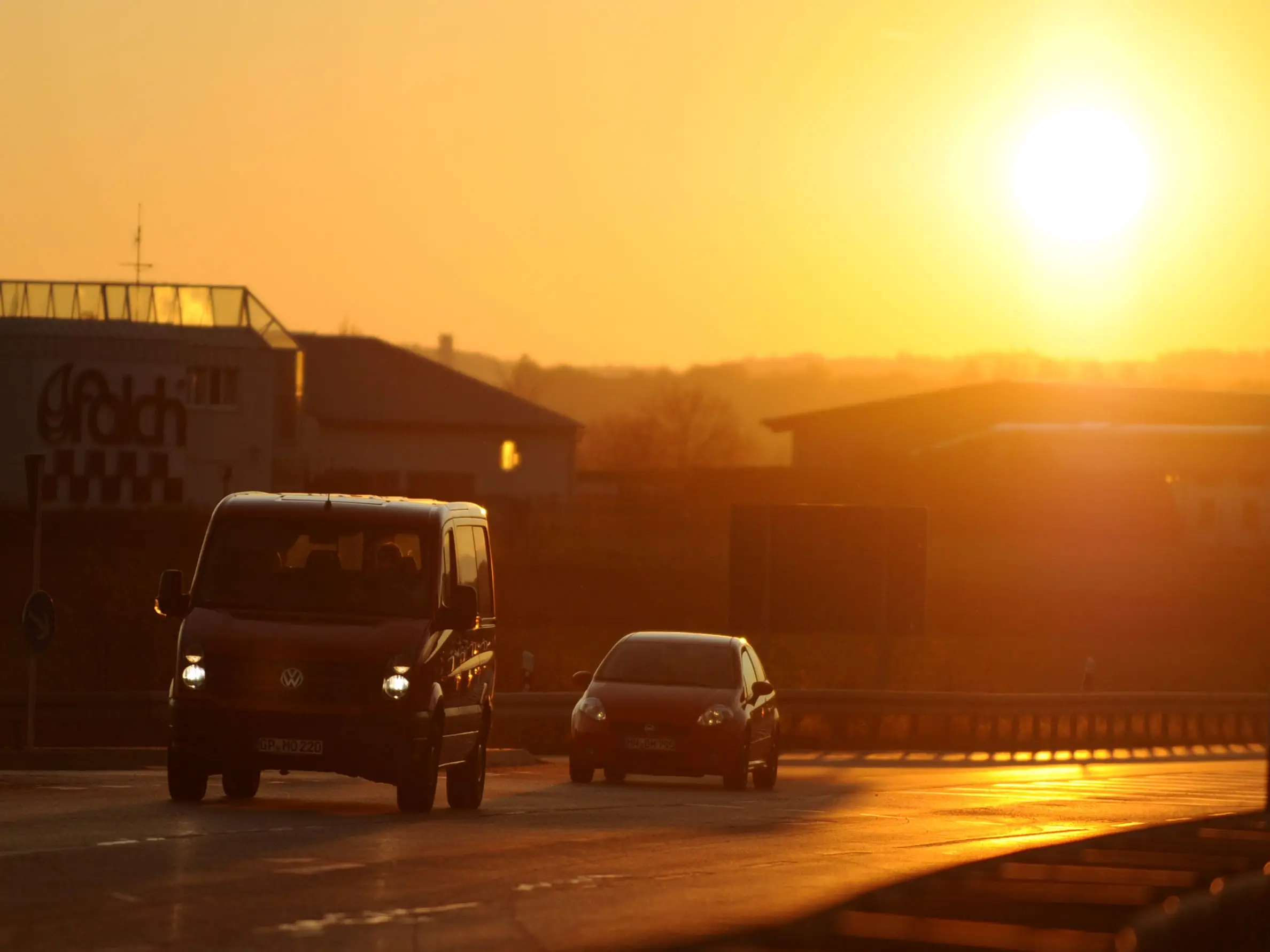 Cars driving on a road with the sun low in the sky