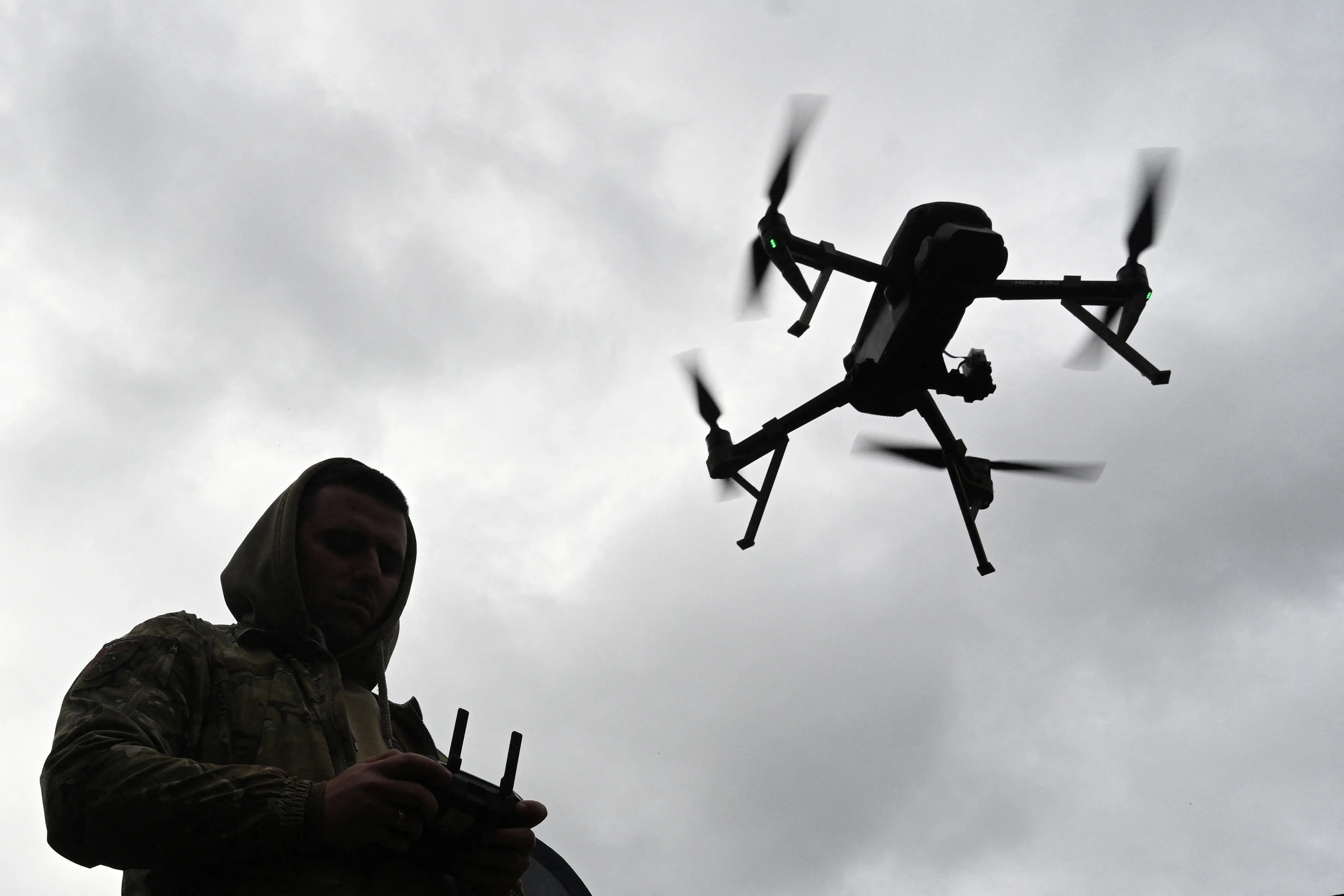 A Ukrainian serviceman pilots a quadcopter drone next to him.