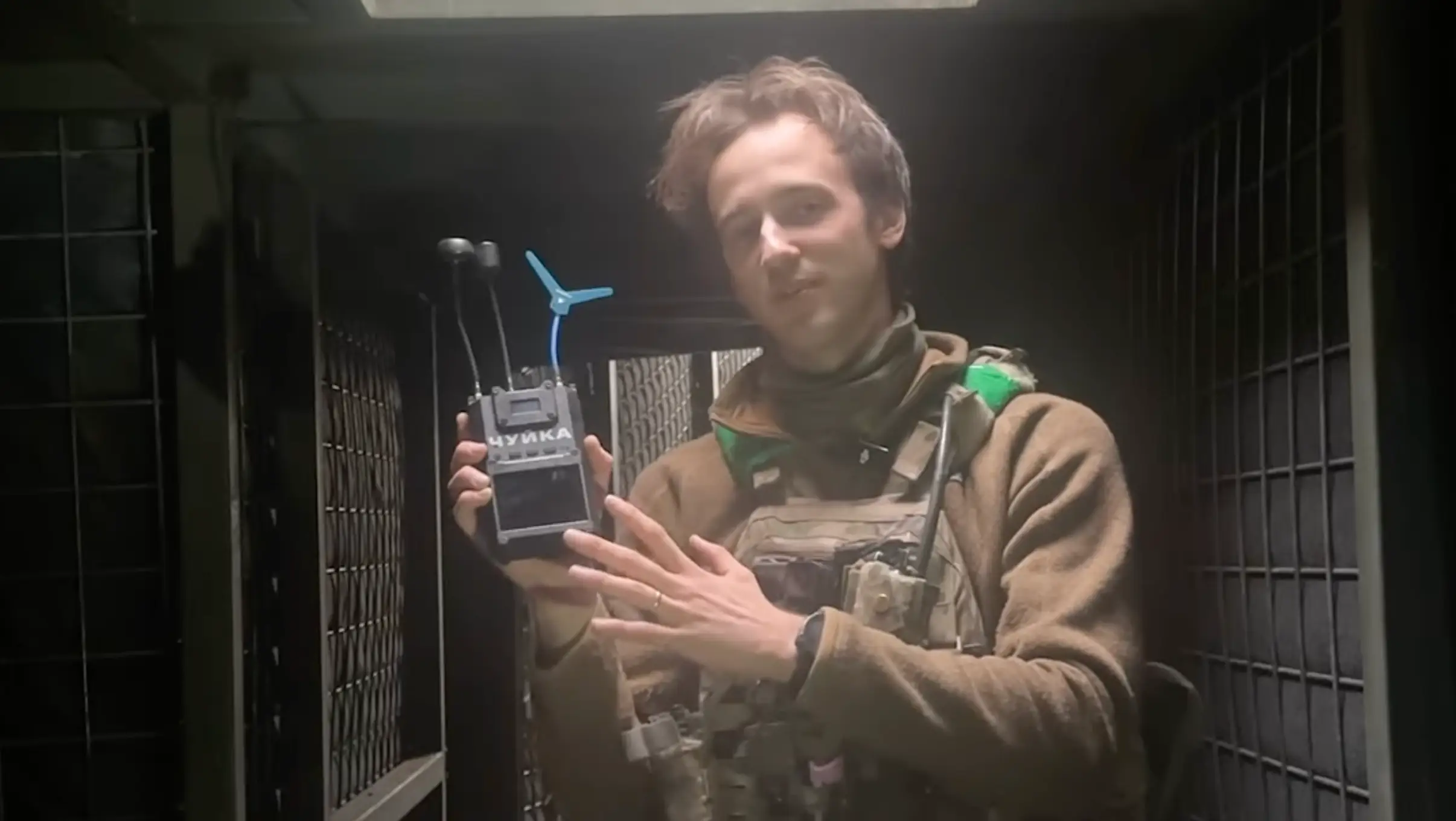 A man in khaki gear stands in an underground position holding a black piece of equipment with multiple antennae