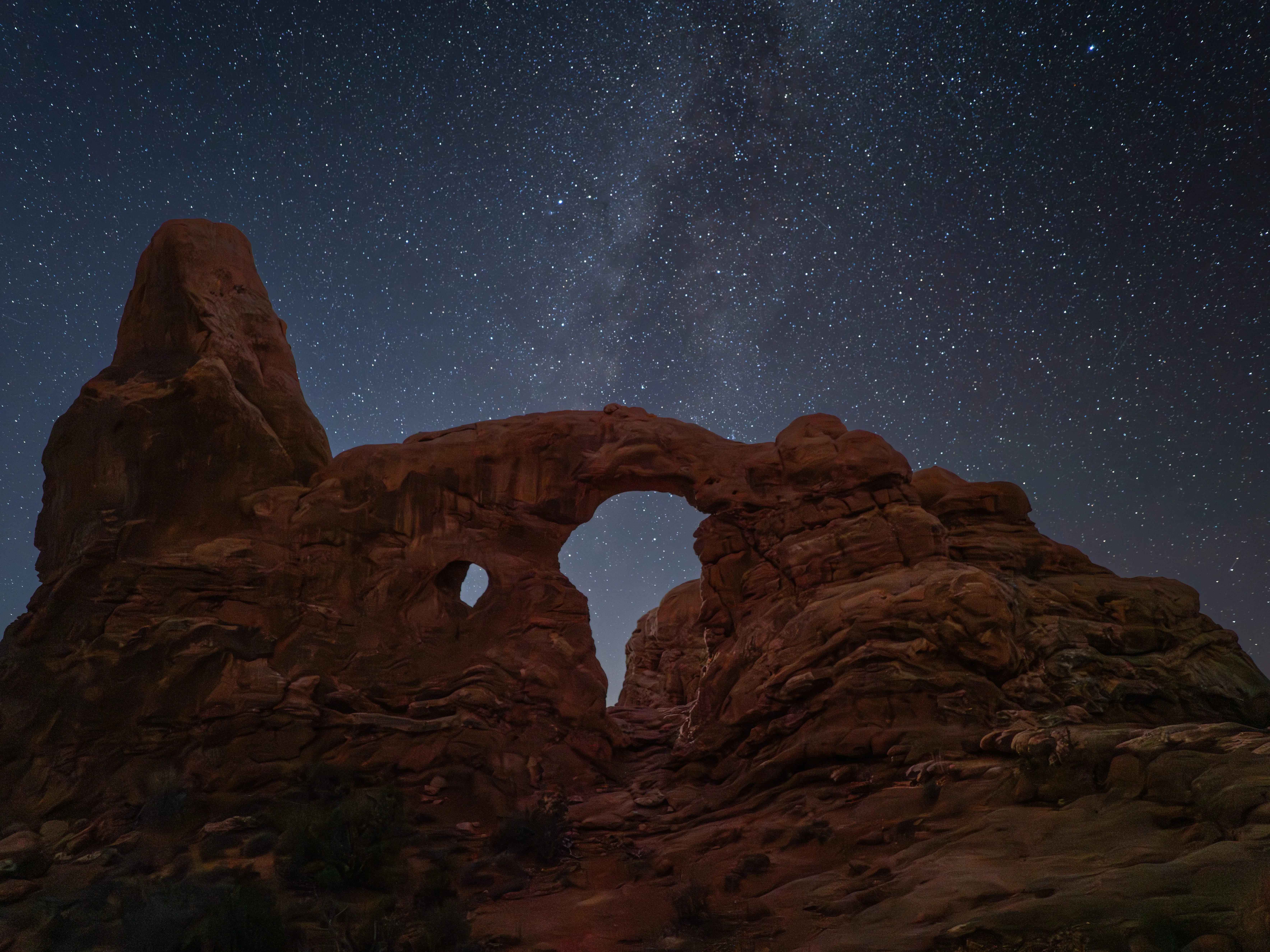 Arches National Park at night with visible stars above rock formations
